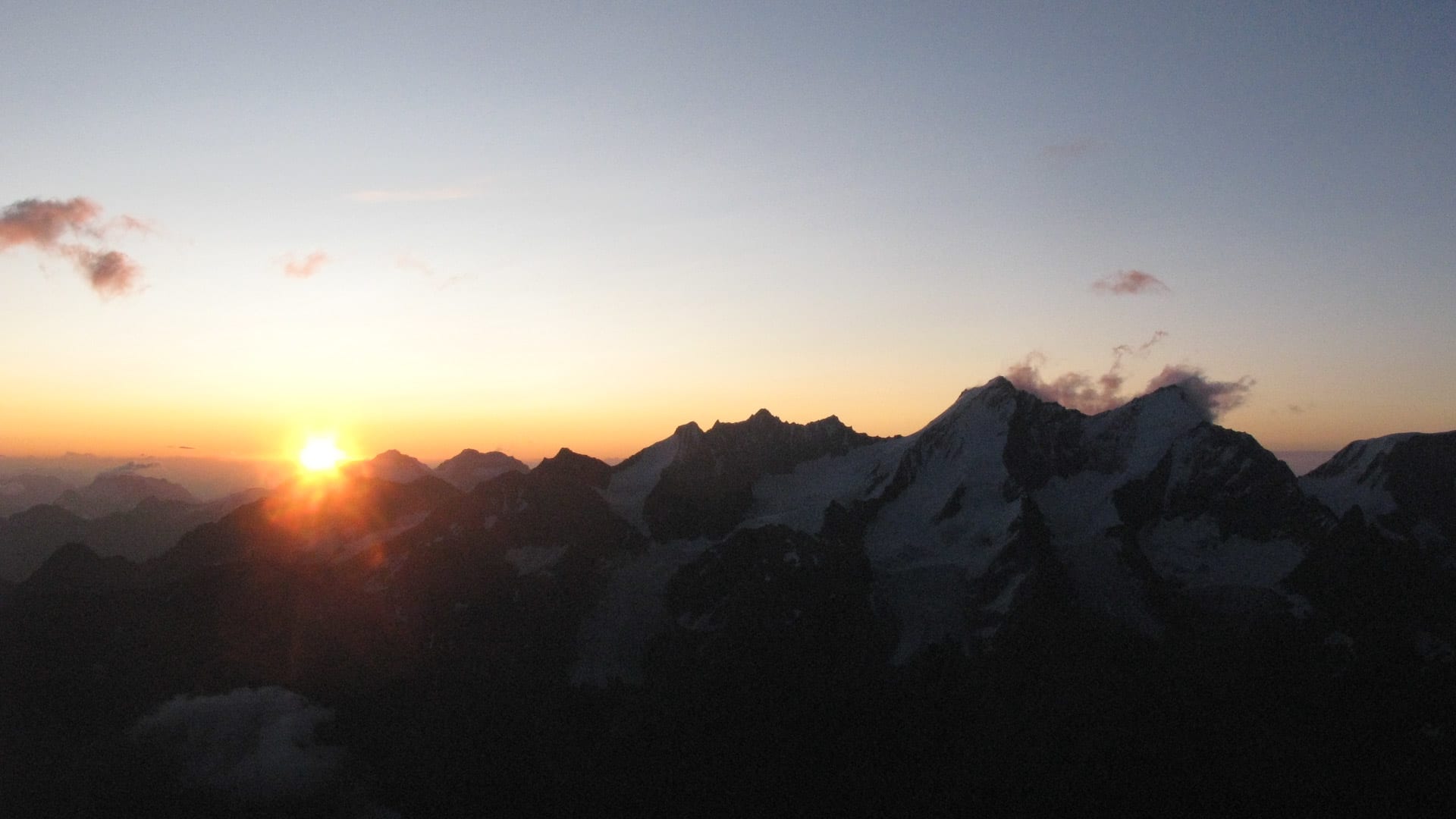 Silhouette des Lyskamms mit schneebedeckten Gipfeln und Gletscherflanken beim Sonnenaufgang in den Walliser Alpen.