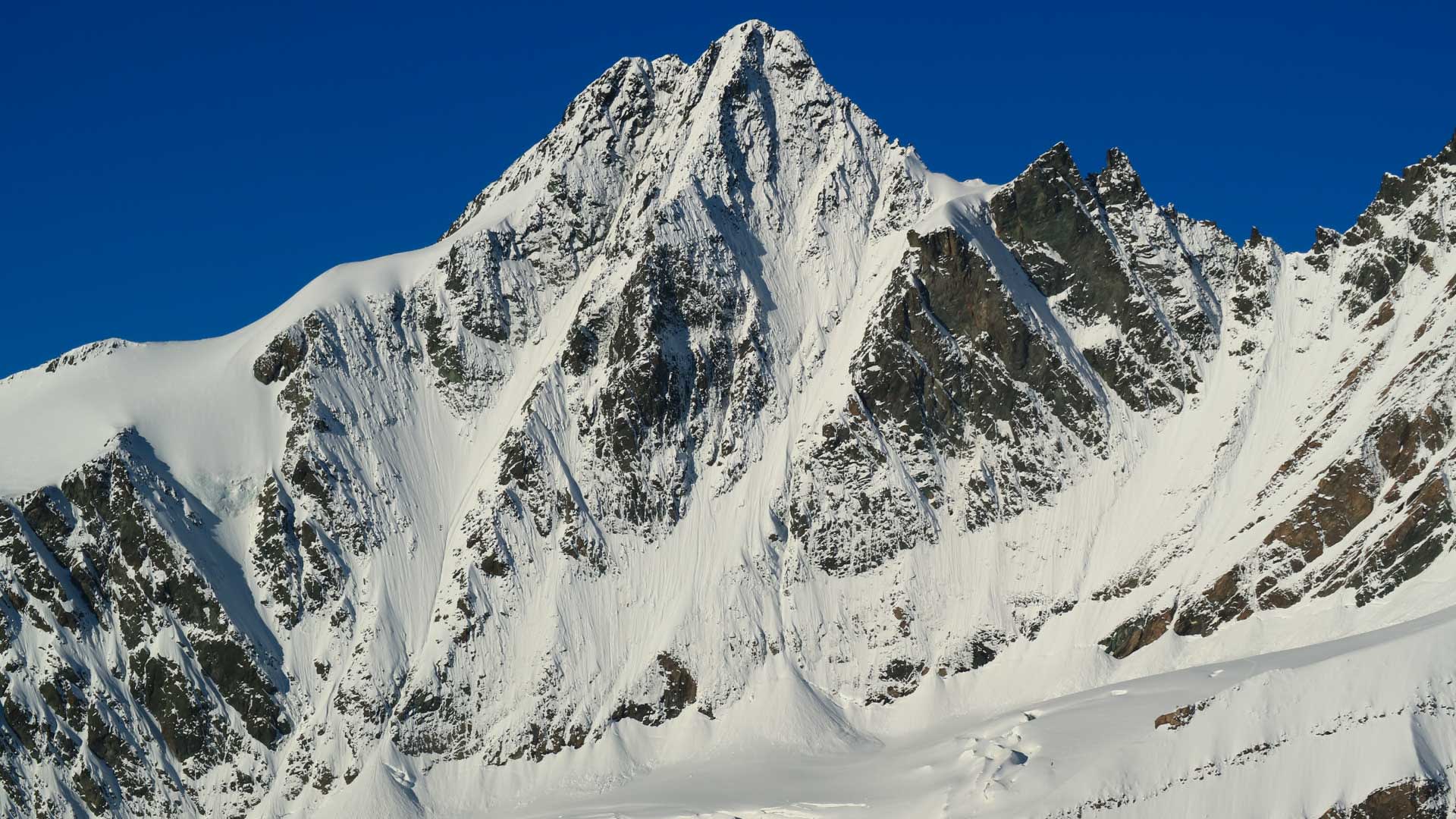 Hochtour Großglockner: Blick auf die Pallavicinirinne mit steiler Felswand, Schneerinnen und pyramidenförmigem Gipfel.