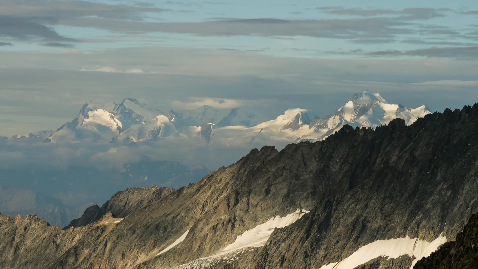 Hochtour im Berner Oberland: Felsige Grate im Vordergrund, dahinter vergletscherte Hochgebirgsgipfel des Wallis im Panorama.