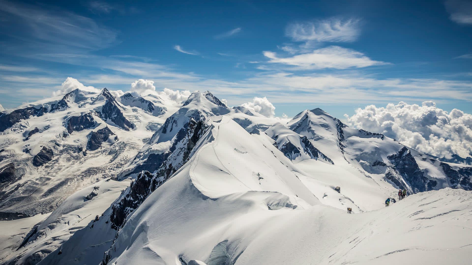 Hochtour Spaghettirunde Zermatt: Bergsteigergruppe auf dem Schneegrat zwischen Castor, Pollux und Breithorn im Panorama.