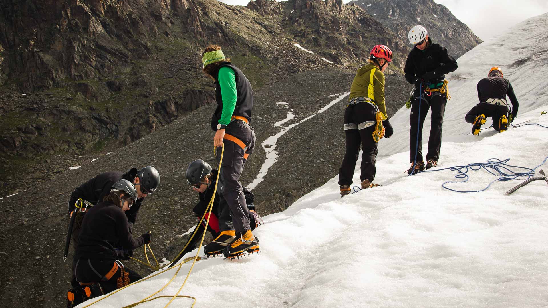 Hochtour im Ötztal: Fünf Bergsteiger mit Steigeisen, Gurten und Helmen üben Spaltenbergung auf Sommerschneehang.