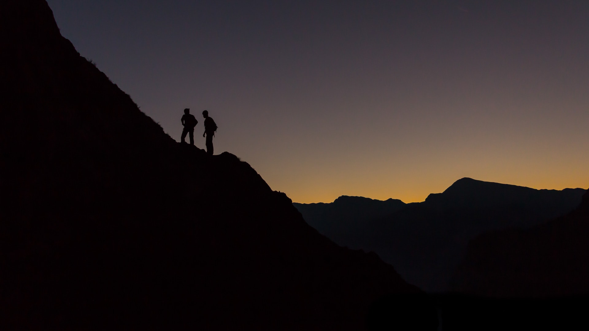 Klettern in der Watzmann Ostwand: zwei Kletterer als Silhouetten beim Aufbruch in der Morgendämmerung.