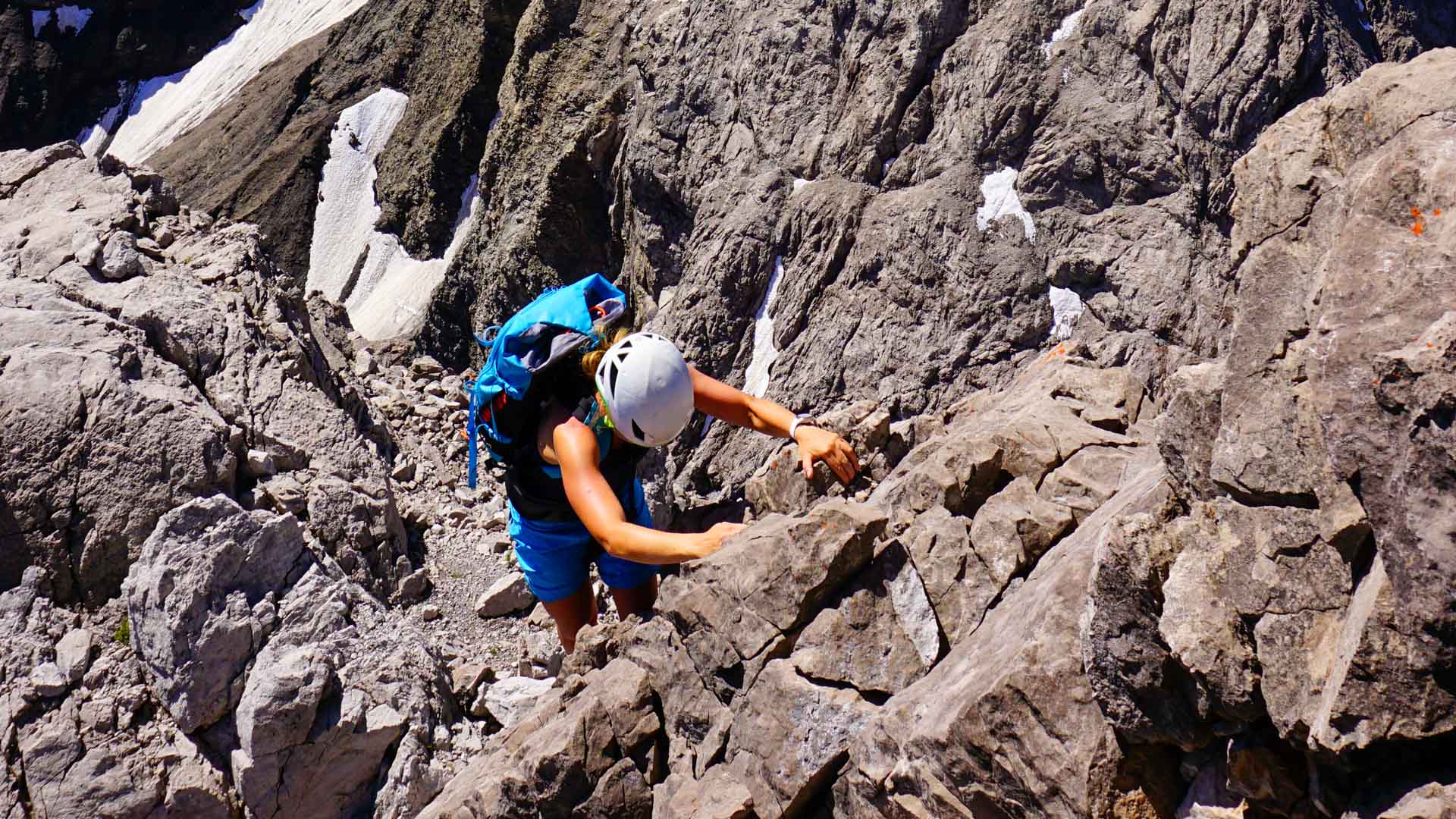 Kletterer in blauem Helm steigt über geschichteten Kalkfels der Trettach im Allgäu auf.