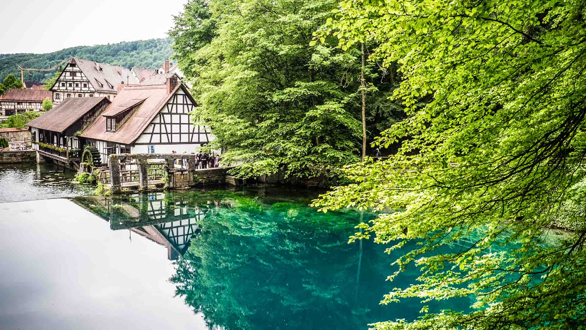 Türkisblauer Blautopf mit historischen Fachwerkgebäuden in Blaubeuren, Treffpunkt für Klettern nahe Ulm im Blautal.