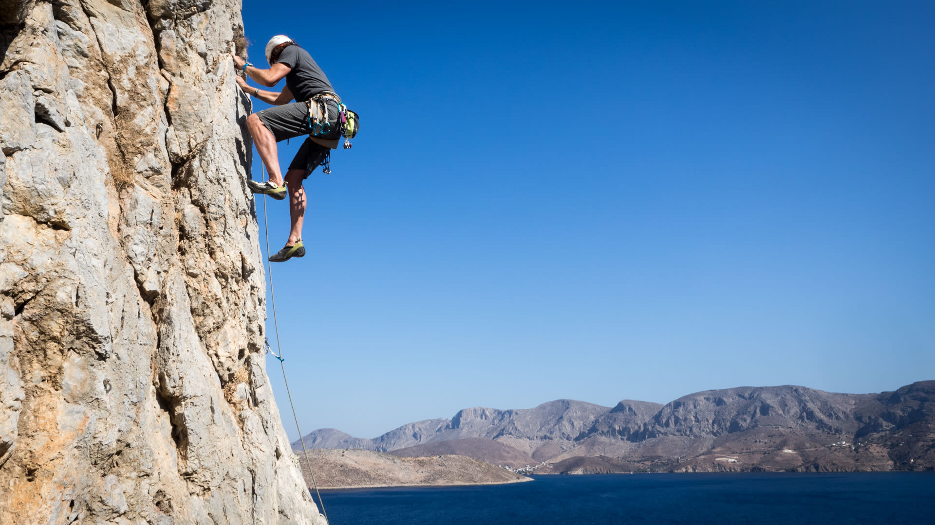 Kletterer steigt an senkrechter Kalksteinwand über dem Meer bei Telendos auf Kalymnos auf.