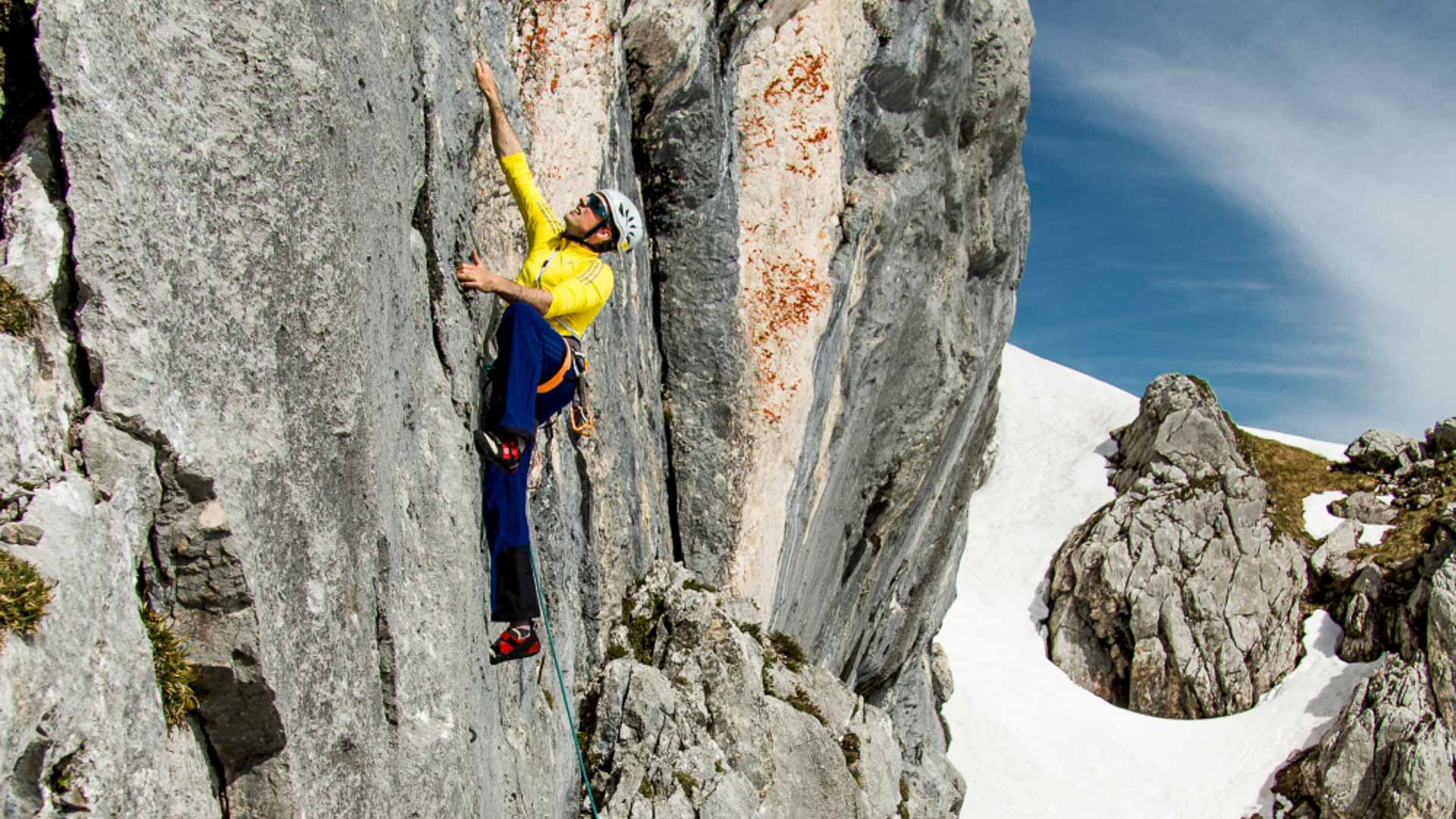 Kletterer in gelbem Trikot steigt an hellem Kalksteinfels mit Expressen und türkisfarbenem Seil im Wettersteingebirge.