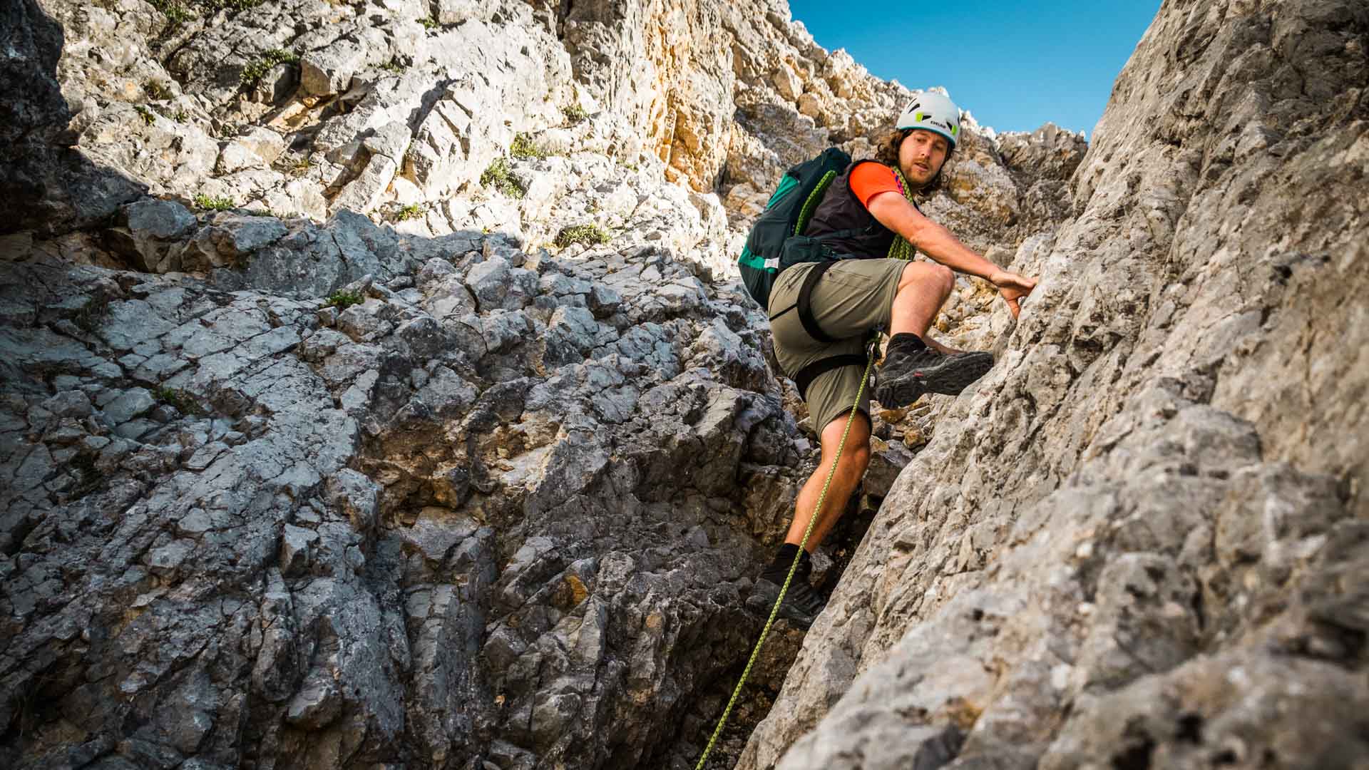 Ein Kletterer steigt mit weißem Helm und Seil in der Roten Rampe zum Großen Band der Watzmann-Wiederroute auf.