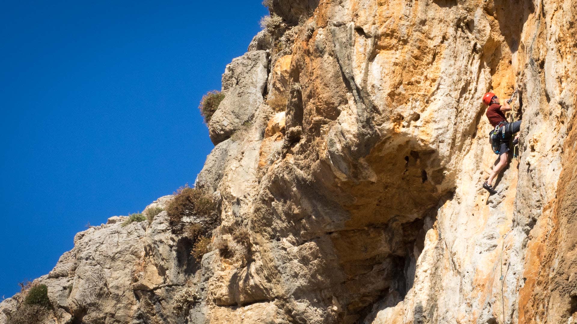 Kletterer im Vorstieg an überhängender Kalksteinwand mit ausgeprägten Erosionsstrukturen auf Kalymnos.