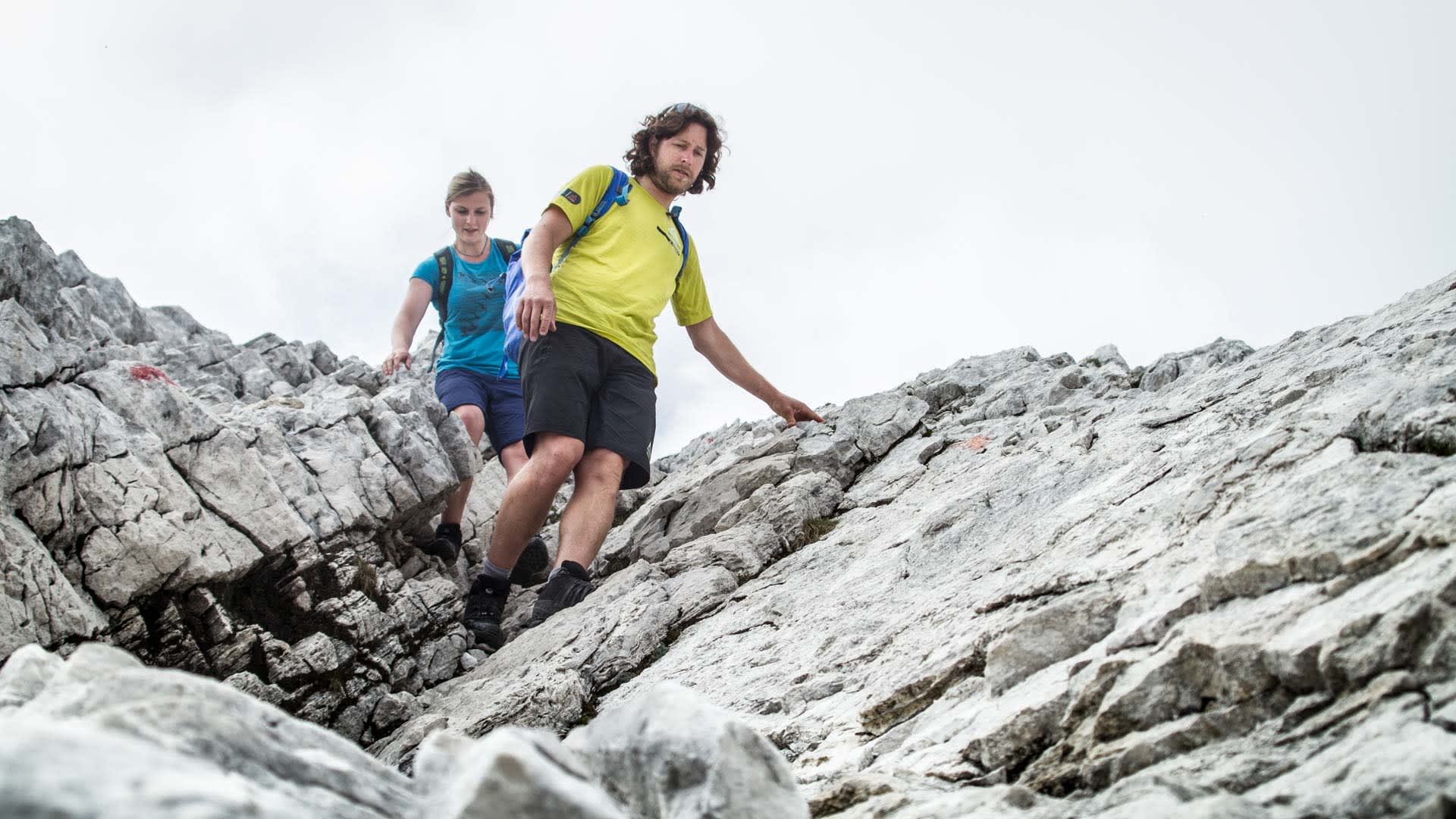 Zwei Klettersteiggeher steigen über den Nordwandsteig am zerklüfteten Kalkfels der Alpspitze ab.