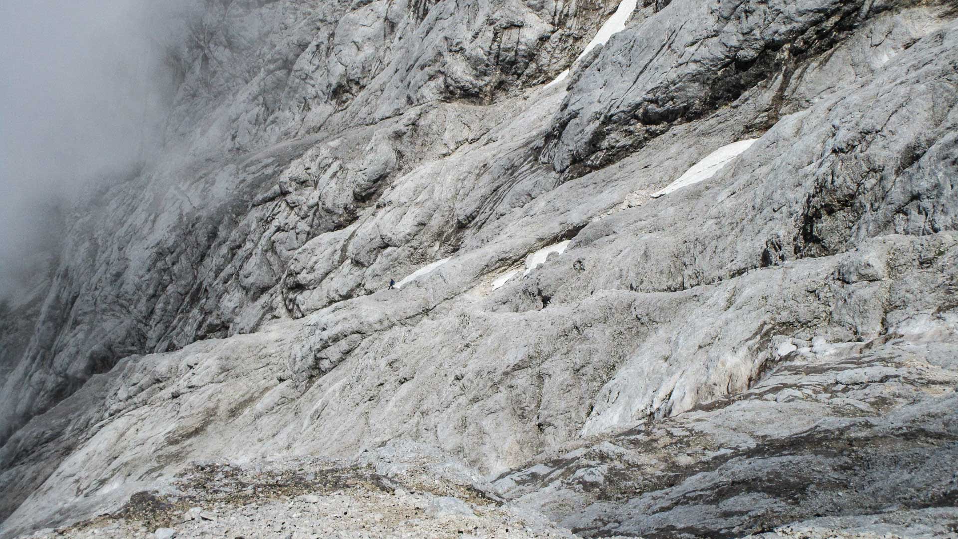 Klettersteig Stopselzieher Zugspitze: drei Klettersteiggeher auf einem Felsband in heller Kalksteinwand mit Nebel.