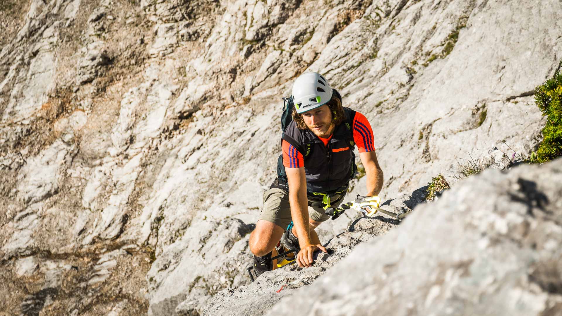 Klettersteig am Untersberg: Kletterer mit weißem Helm und Klettergurt steigt an der hellen Kalkfelswand in den Berchtesgadener