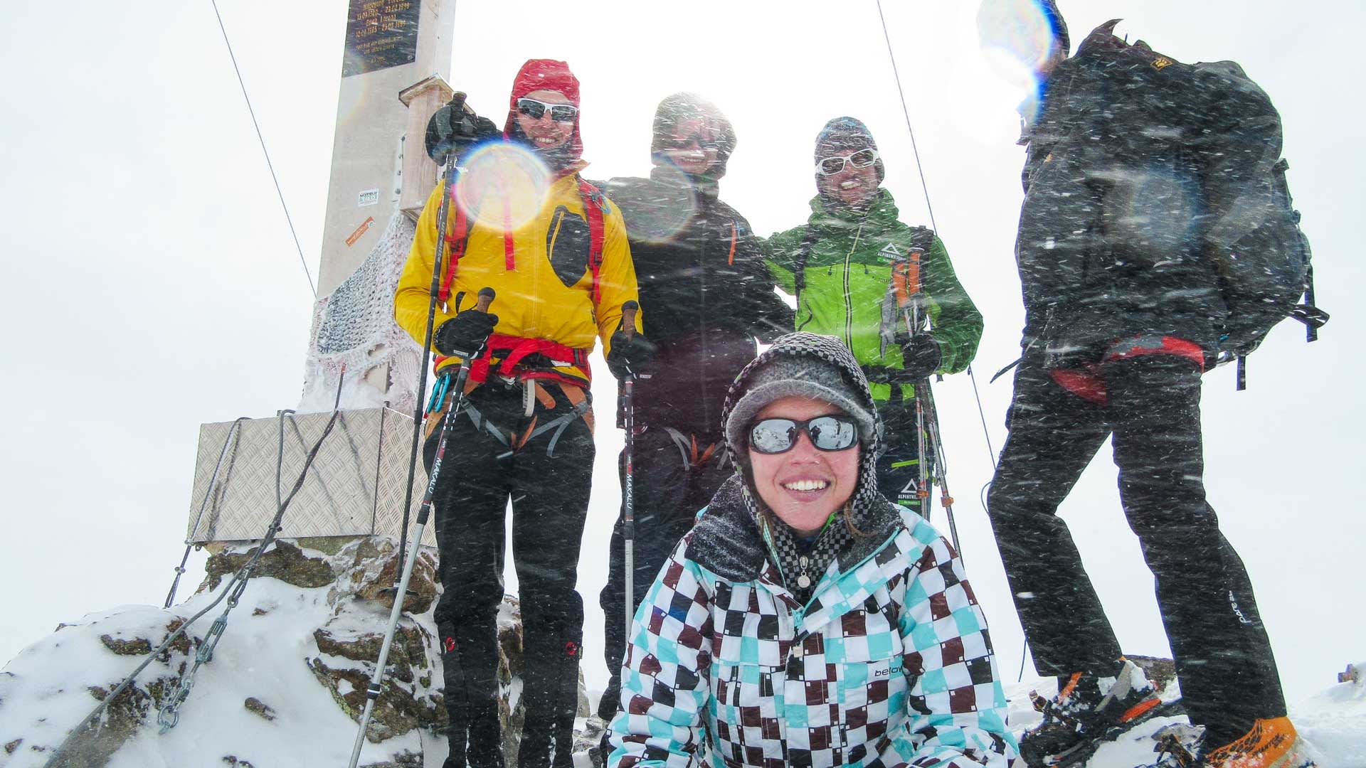 Fünf Schneeschuhwanderer posieren bei Schneetreiben auf einem felsigen Gipfel in der Silvretta.