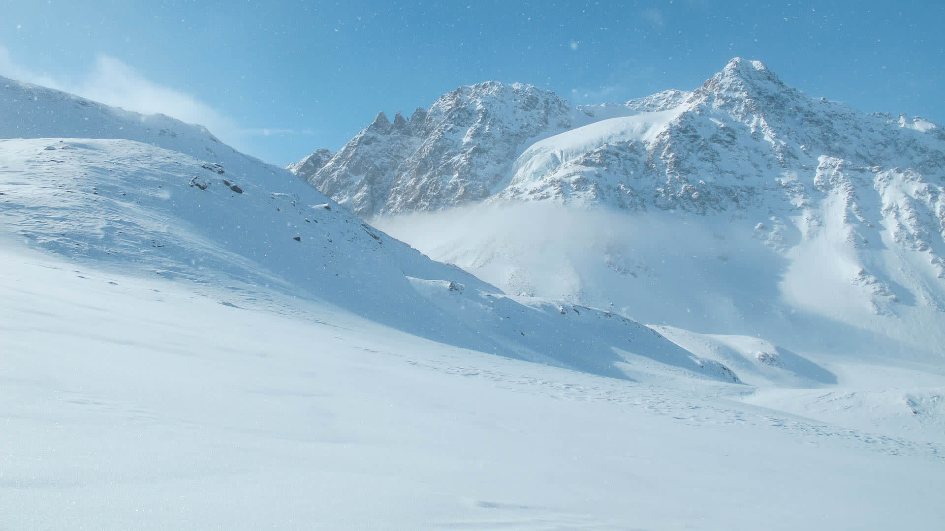Weitläufige Schneefläche mit zwei verschneiten Berggipfeln bei einer Schneeschuhtour rund um die Jamtalhütte in der Silvretta.