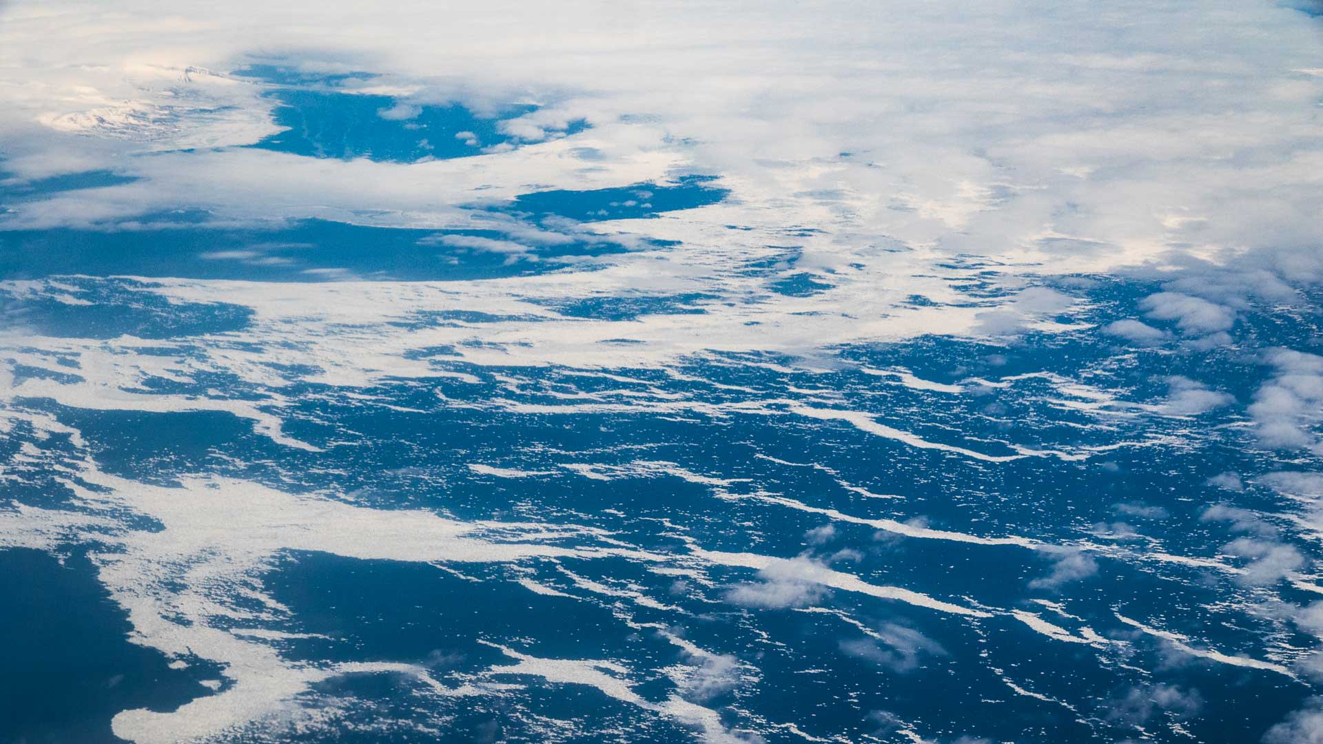 Luftaufnahme des schneebedeckten Geländes rund um Longyearbyen auf Spitzbergen beim Anflug zur Skitouren-Woche.