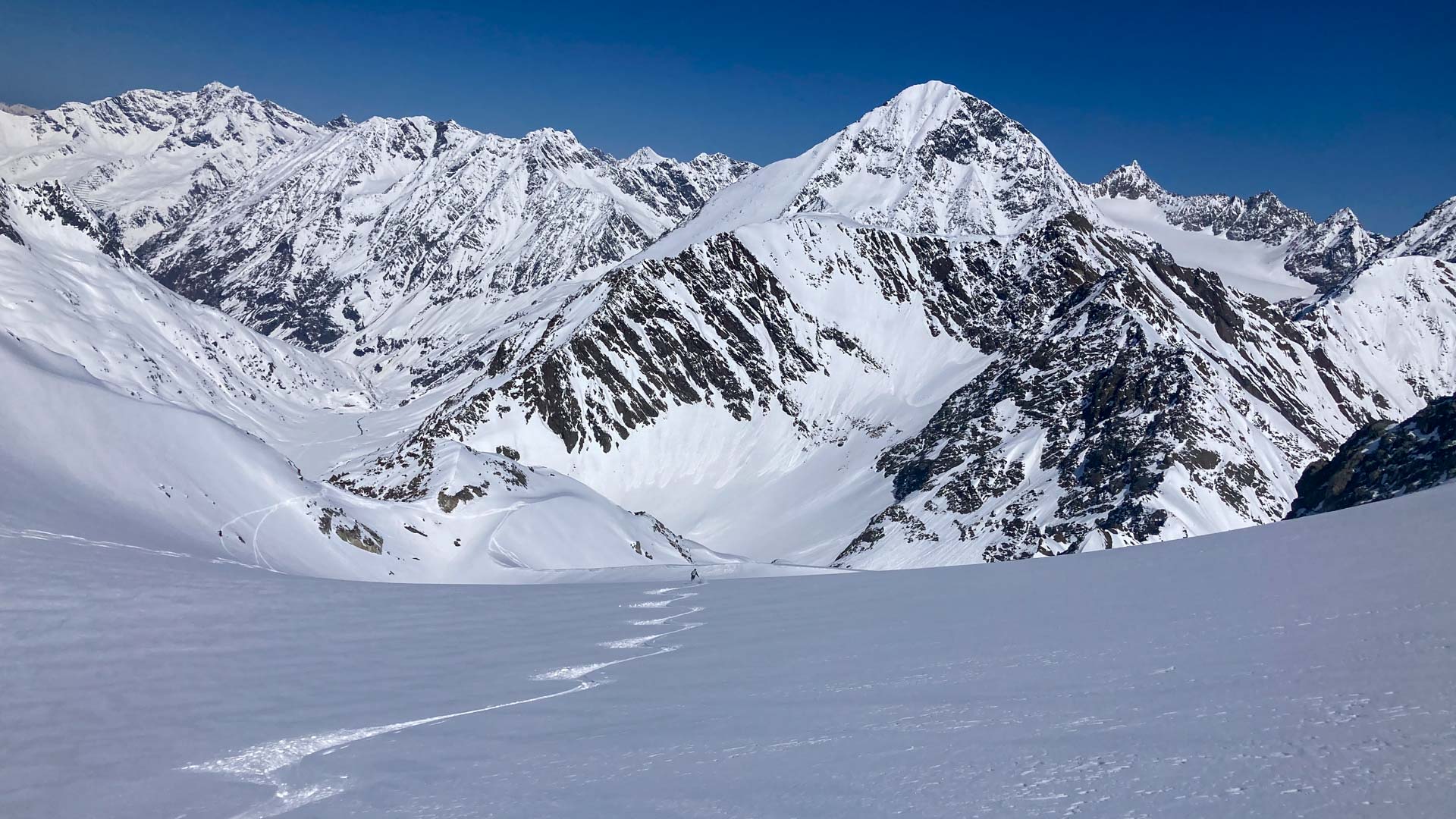 Skitourengeher zieht eine gerade Aufstiegsspur über ein weites Schneefeld am Daunkogel.