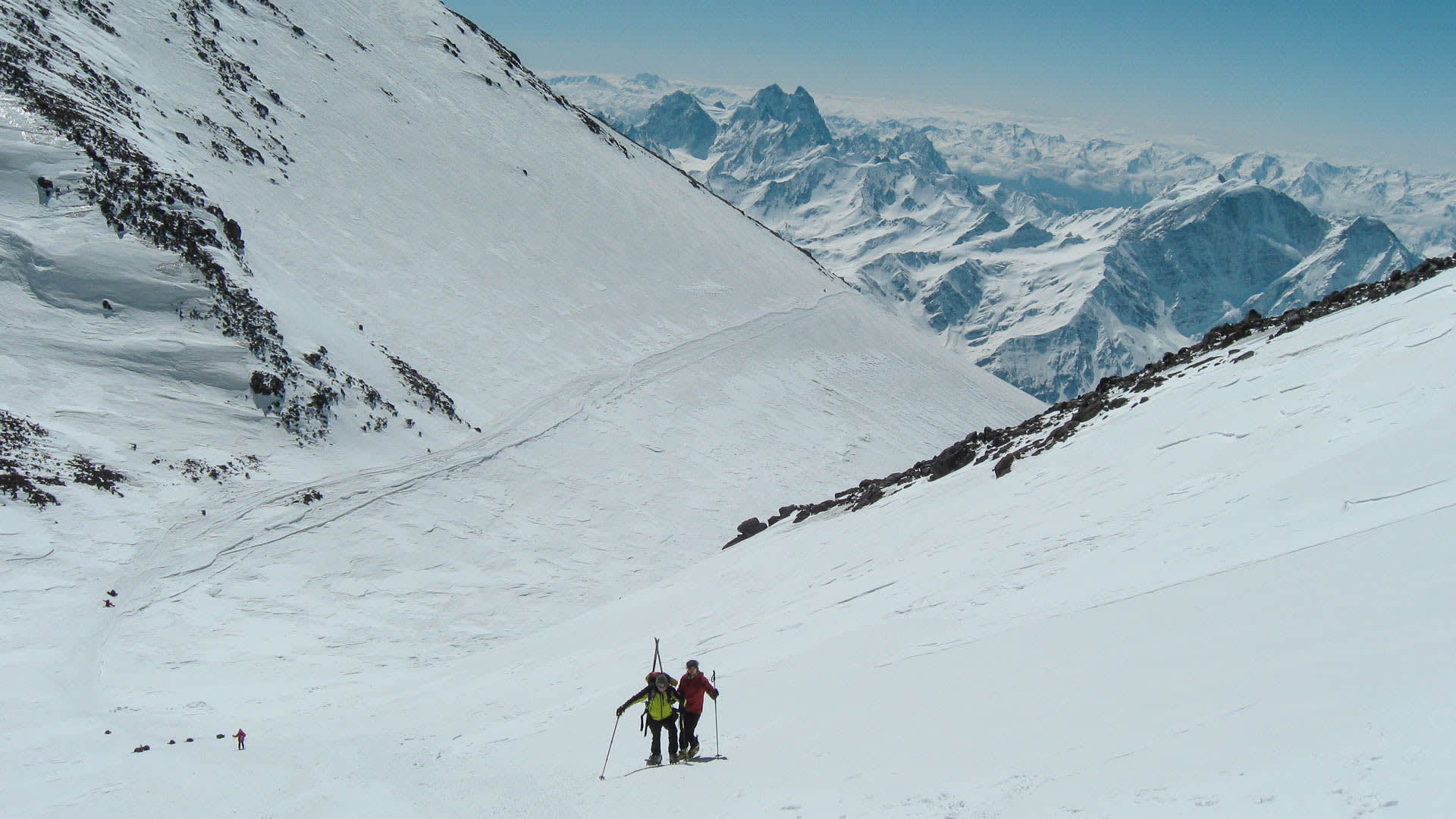 Zwei Skitourengeher steigen einen schneebedeckten Hang am Elbrus in Russland auf.