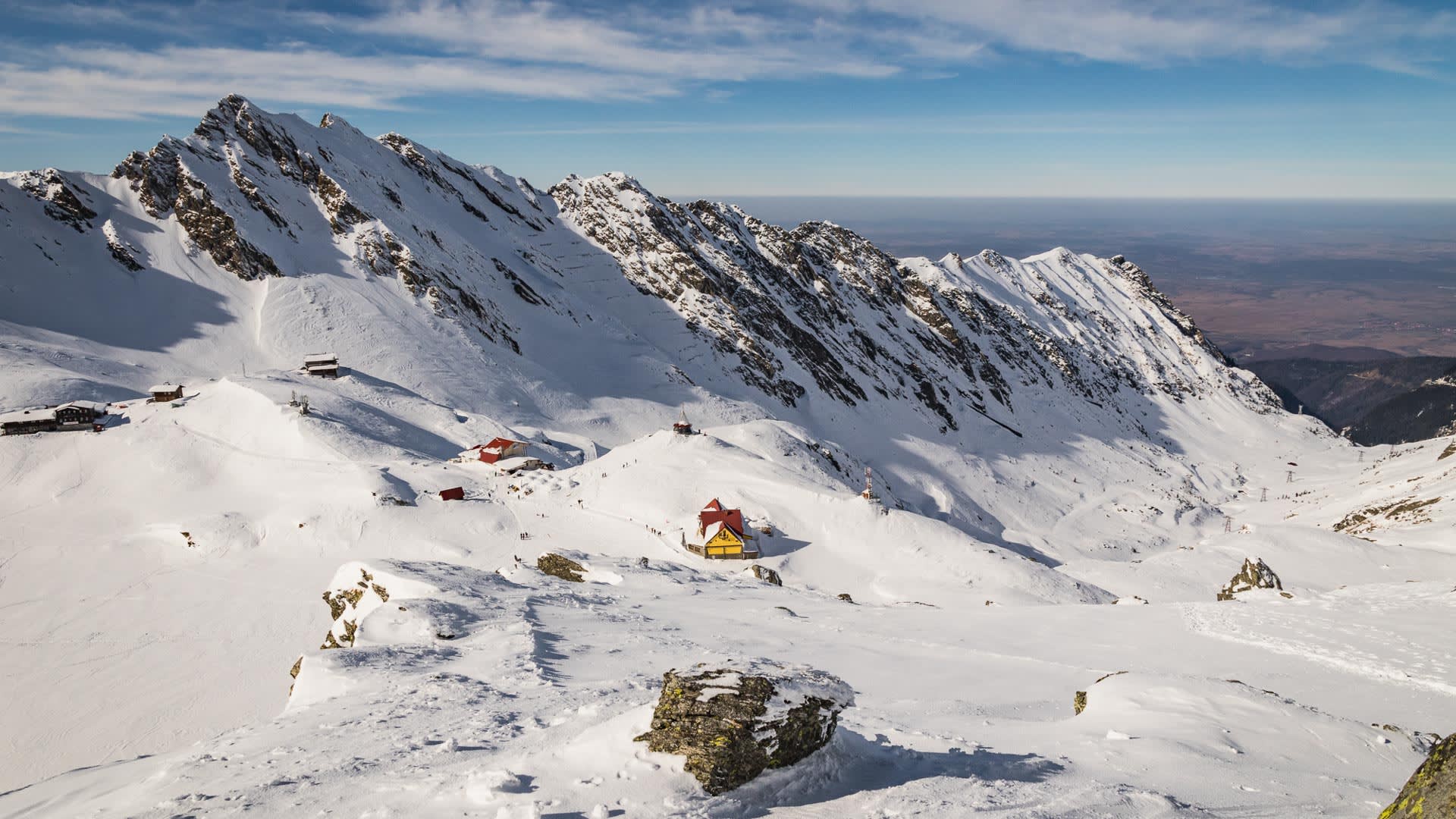 Skitour in den rumänischen Karpaten: Panoramablick auf das verschneite Hochplateau am Balea Lac mit Hütten