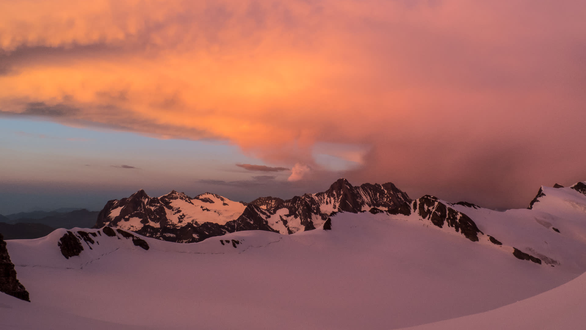 Skitour Berner Oberland: Weitläufiges Gletscherfeld in rosa-orangenem Abendlicht mit dunklen Felsgipfeln