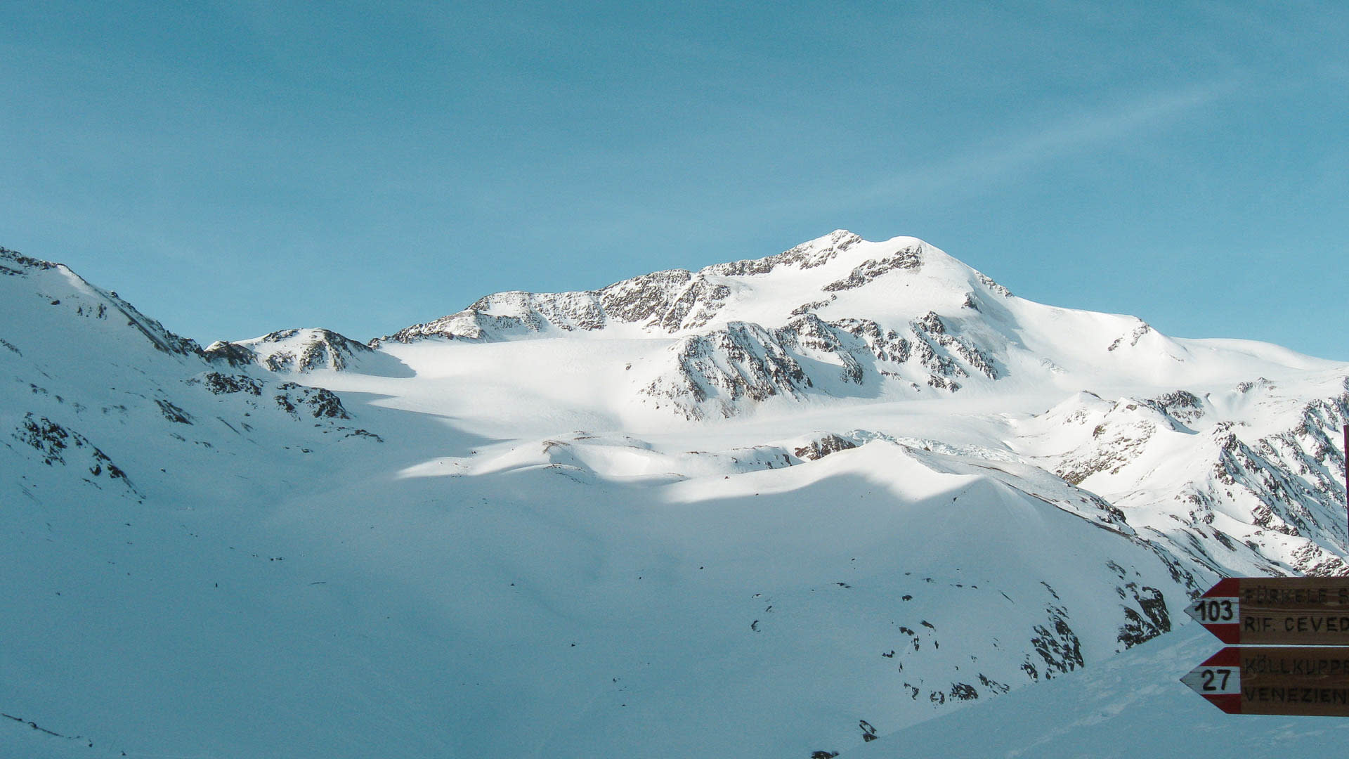 Skitour im Ortlergebiet: schneebedeckter Gipfelaufbau mit Gletscherplateau und Wegweiser zum Rifugio Cevedale.