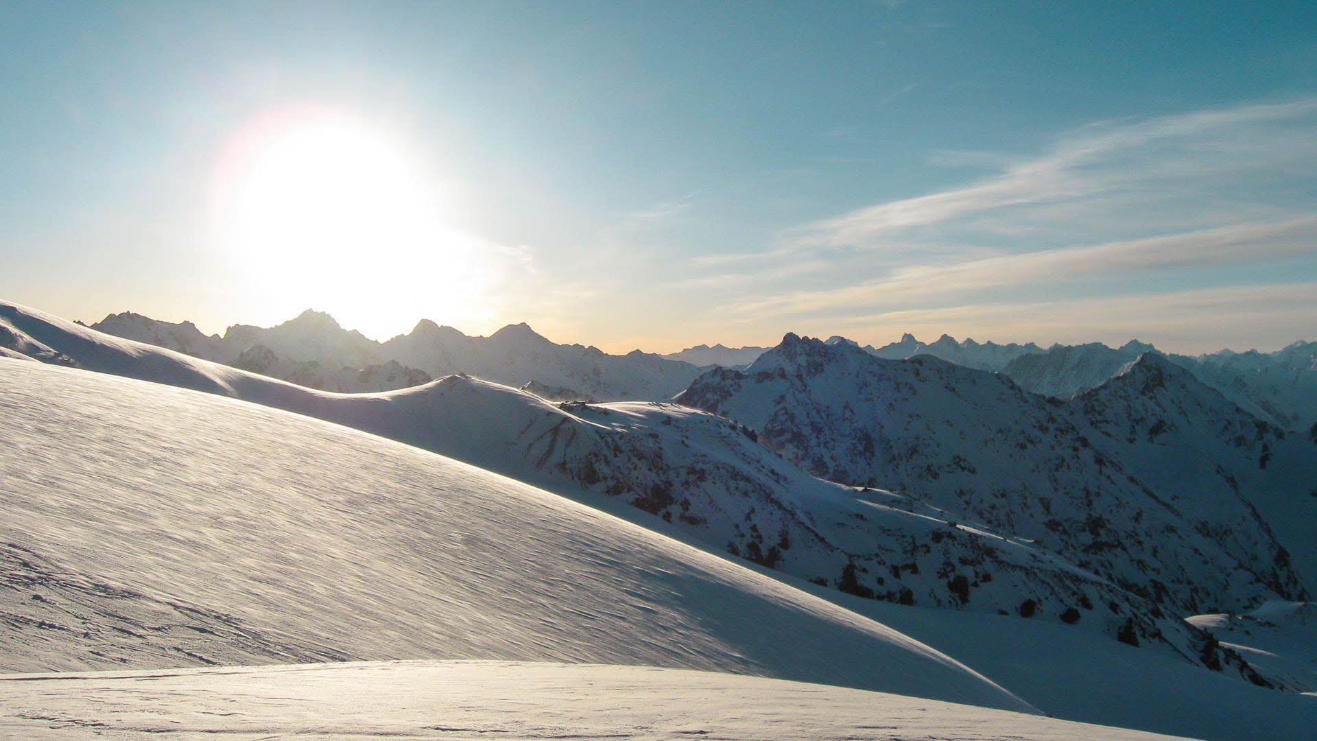 Skitour am Elbrus: windgeformtes Hochplateau mit tiefstehender Sonne und Kaukasus-Panorama im Gegenlicht.