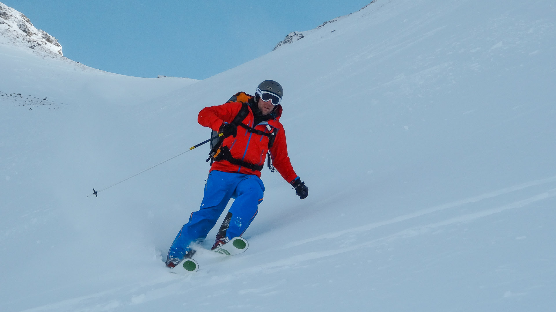 Freerider in roter Jacke fährt einen unverspurten Steilhang vor felsigem Gipfel in Garmisch ab.