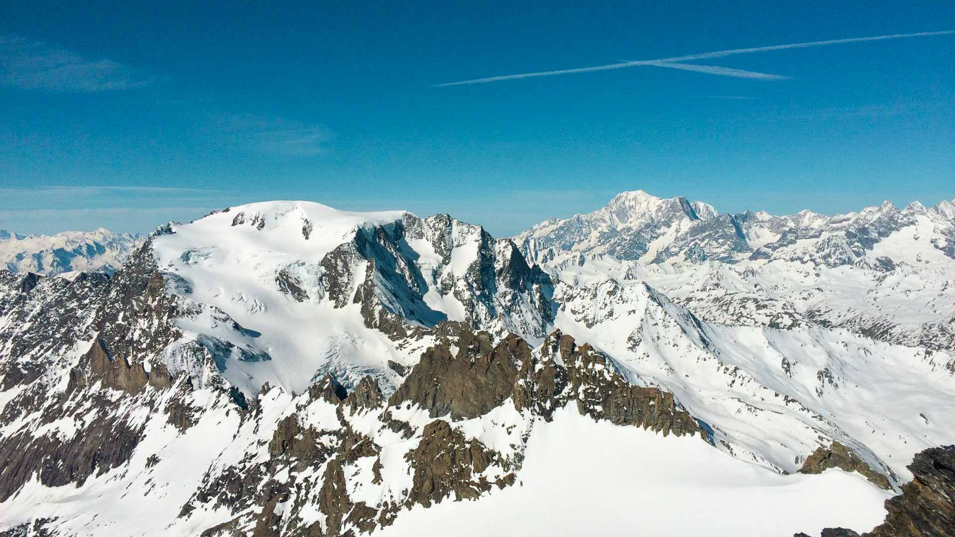 Skitour im Mont-Blanc-Massiv: Hochalpines Panorama mit vergletschertem Gipfel, Felsgrat und tiefblauem Himmel.