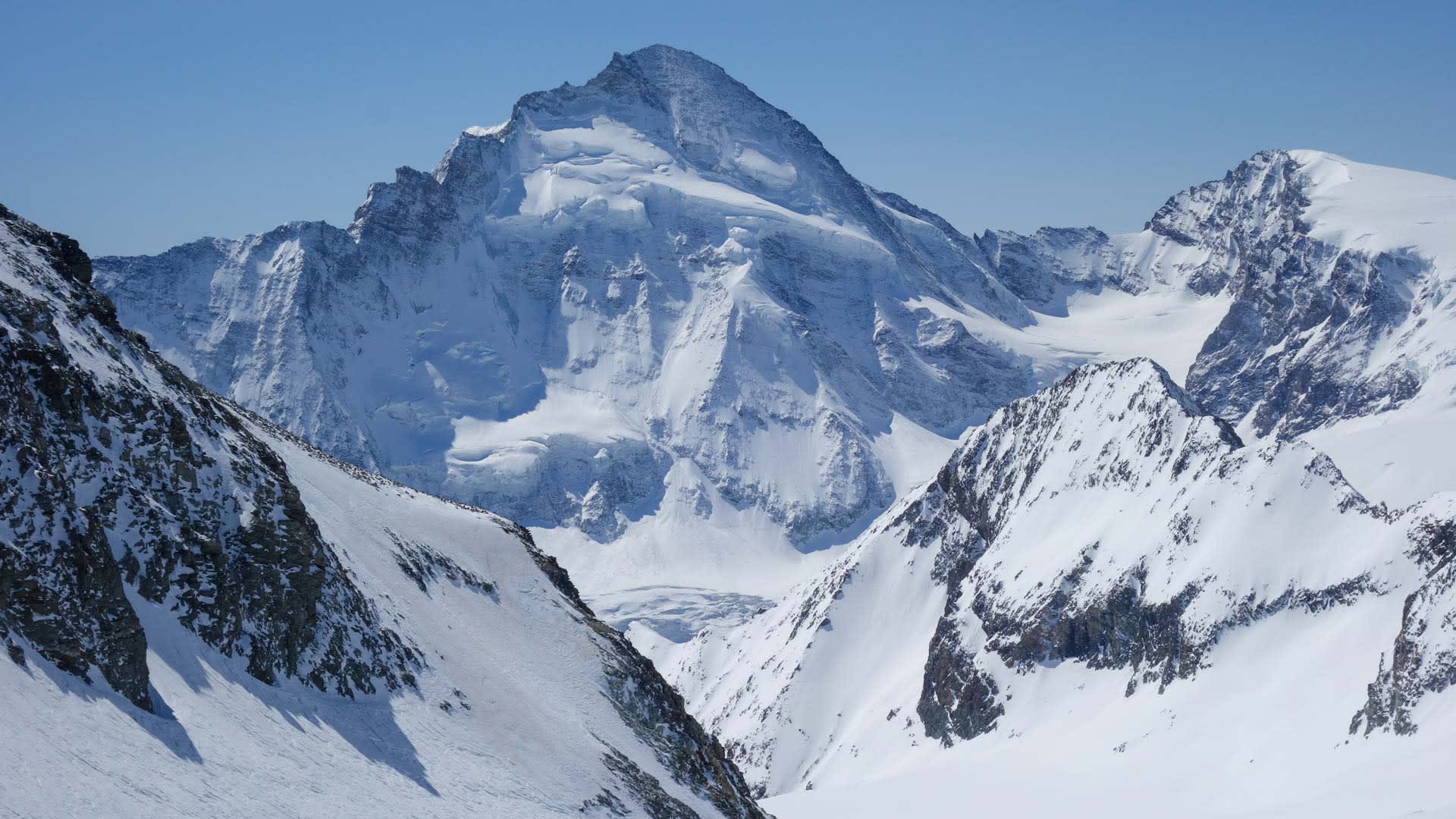 Weitwinkel-Panorama eines Gletscherbeckens mit pyramidenförmigem Gipfel, Seracs und klarem Winterhimmel in den Walliser Alpen.