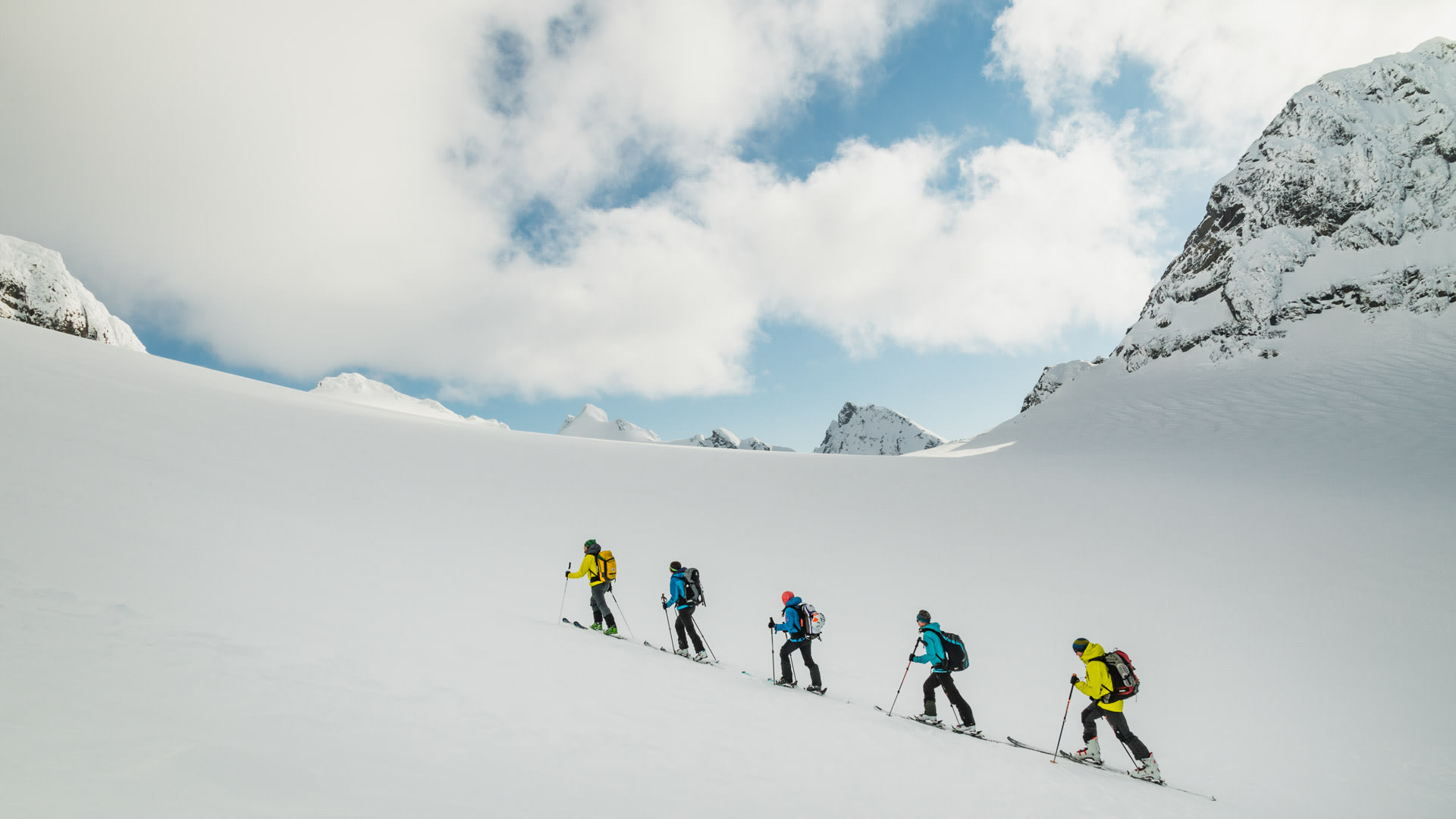 Fünf Skitourengeher steigen mit Fellen in Einerreihung den Schneehang zum Tafeltinden auf.