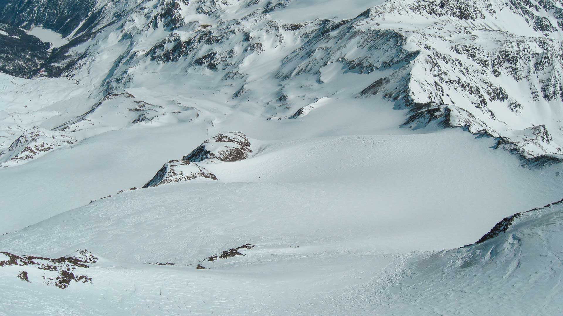 Skitour auf einem schneebedeckten Gletscherplateau in Südtirol mit kleiner Gruppe im Aufstieg.