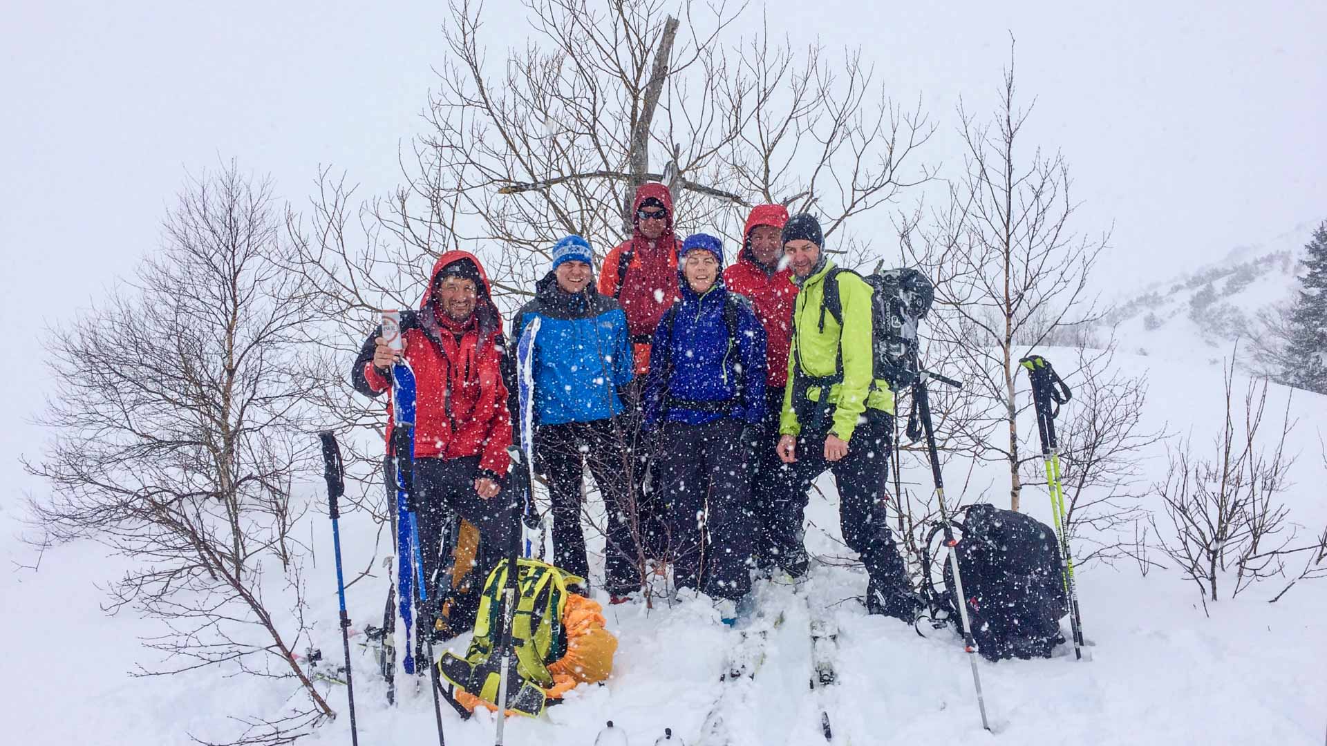 Sieben Skitourengeher posieren bei starkem Schneefall für ein Gruppenfoto im Durmitor-Nationalpark.