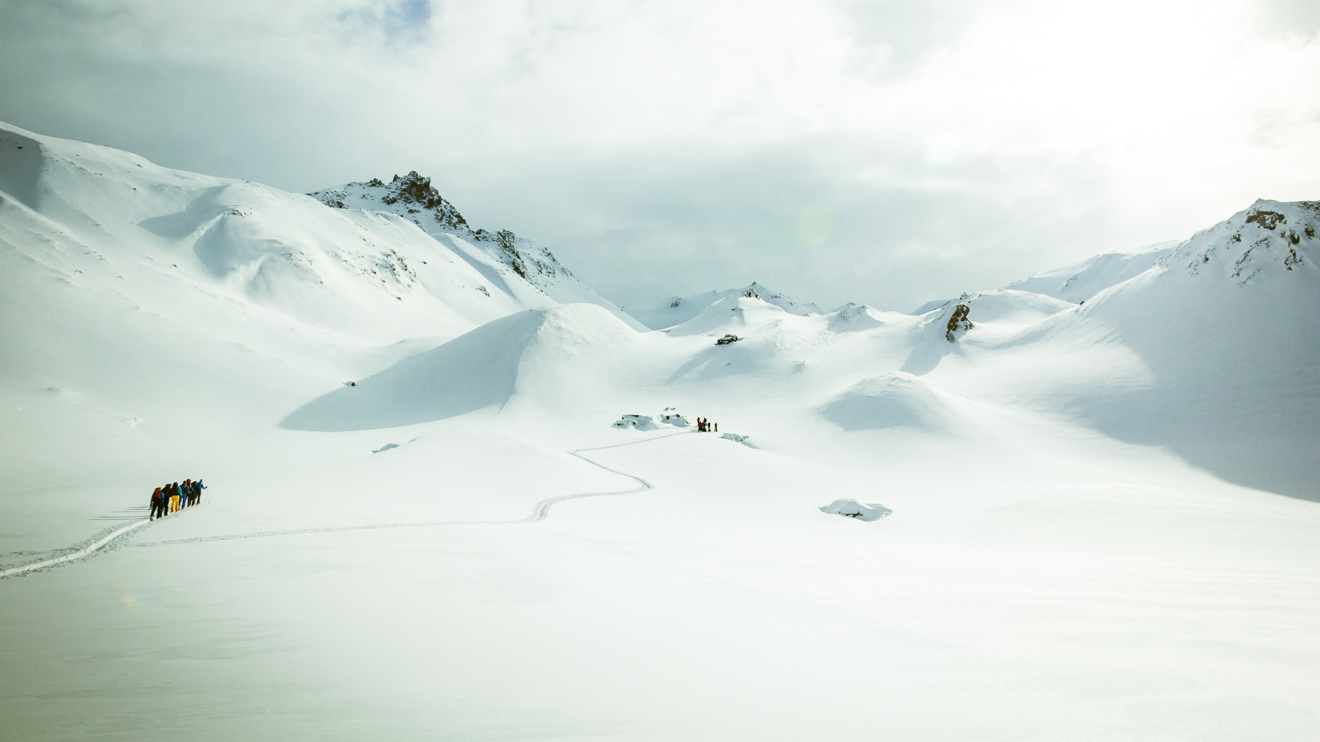 Gruppe von 7–8 Skitourengehern steht auf einem flachen Schneplateau in der Silvretta bei der Jamtalhütte.