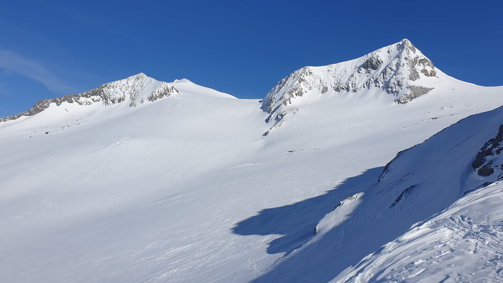 Schneebedecktes Hochplateau am Großvenediger mit zwei Gipfeln und Skispuren auf dem Gletscher der Hohen Tauern.
