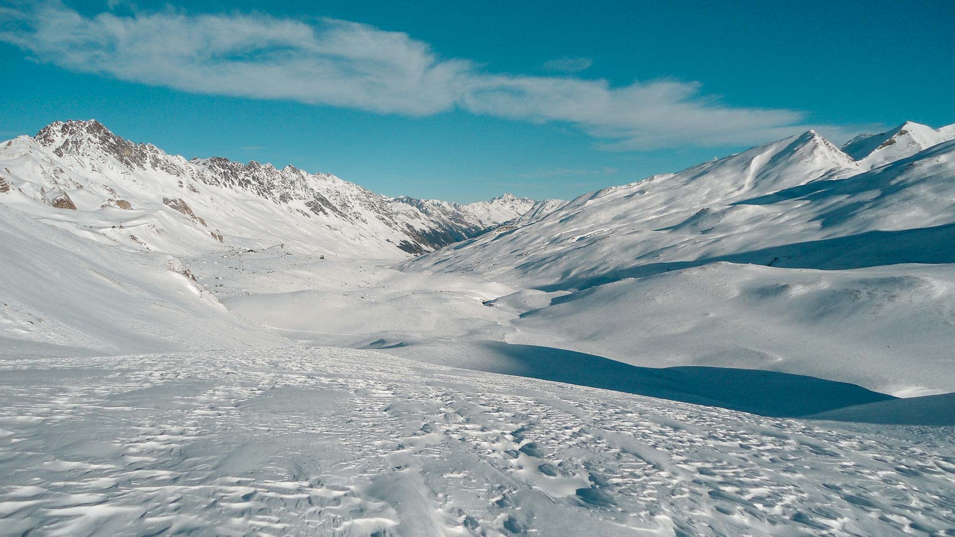 Verschneites Hochtal in der Silvretta mit felsigem Gebirgskamm und windgeprägter Schneeoberfläche im Winter.