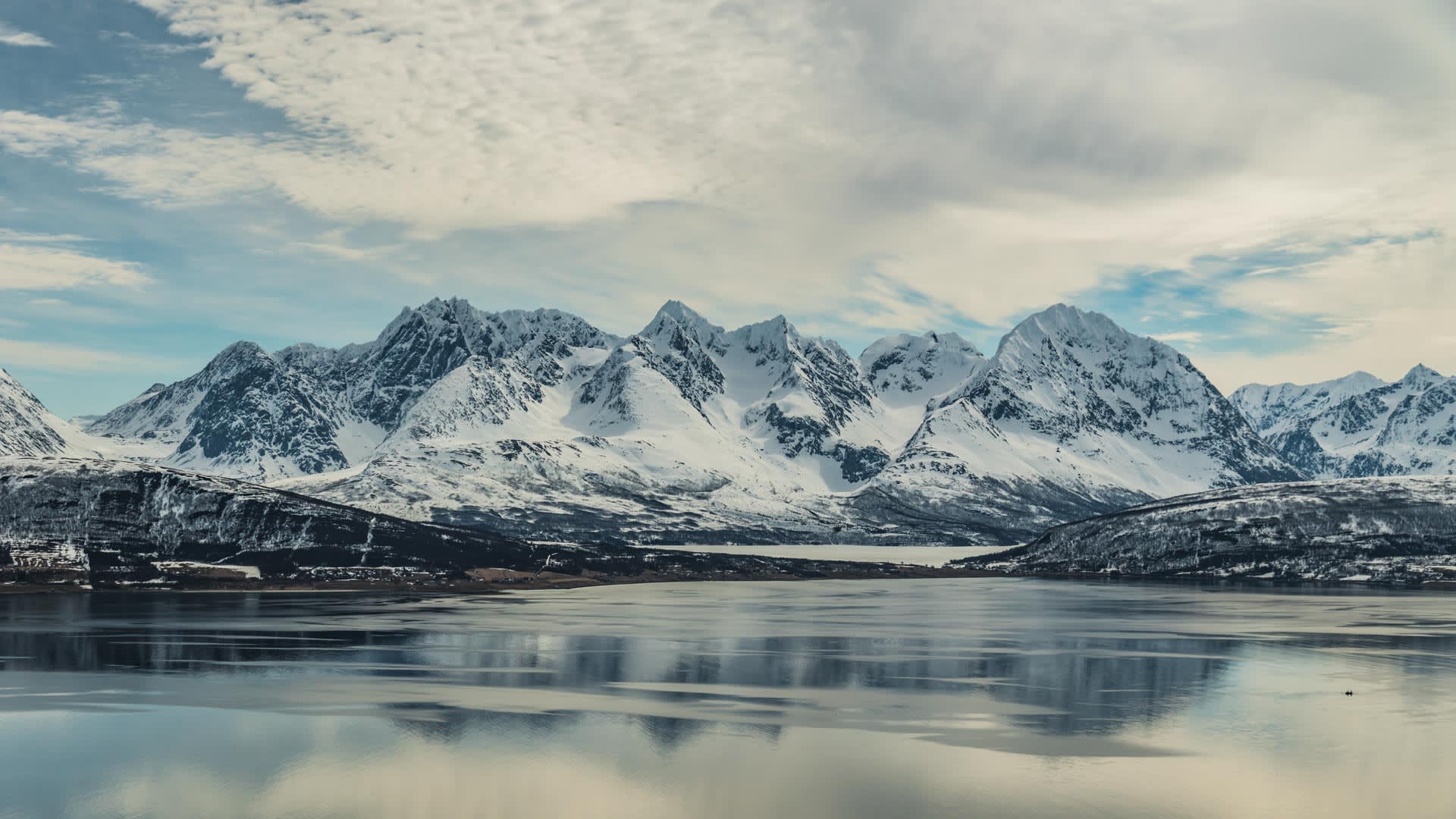 Skitour Lyngen Alps: Winterliches Fjordpanorama mit vergletscherten, schneebedeckten Gipfeln und spiegelnder Wasseroberfläche
