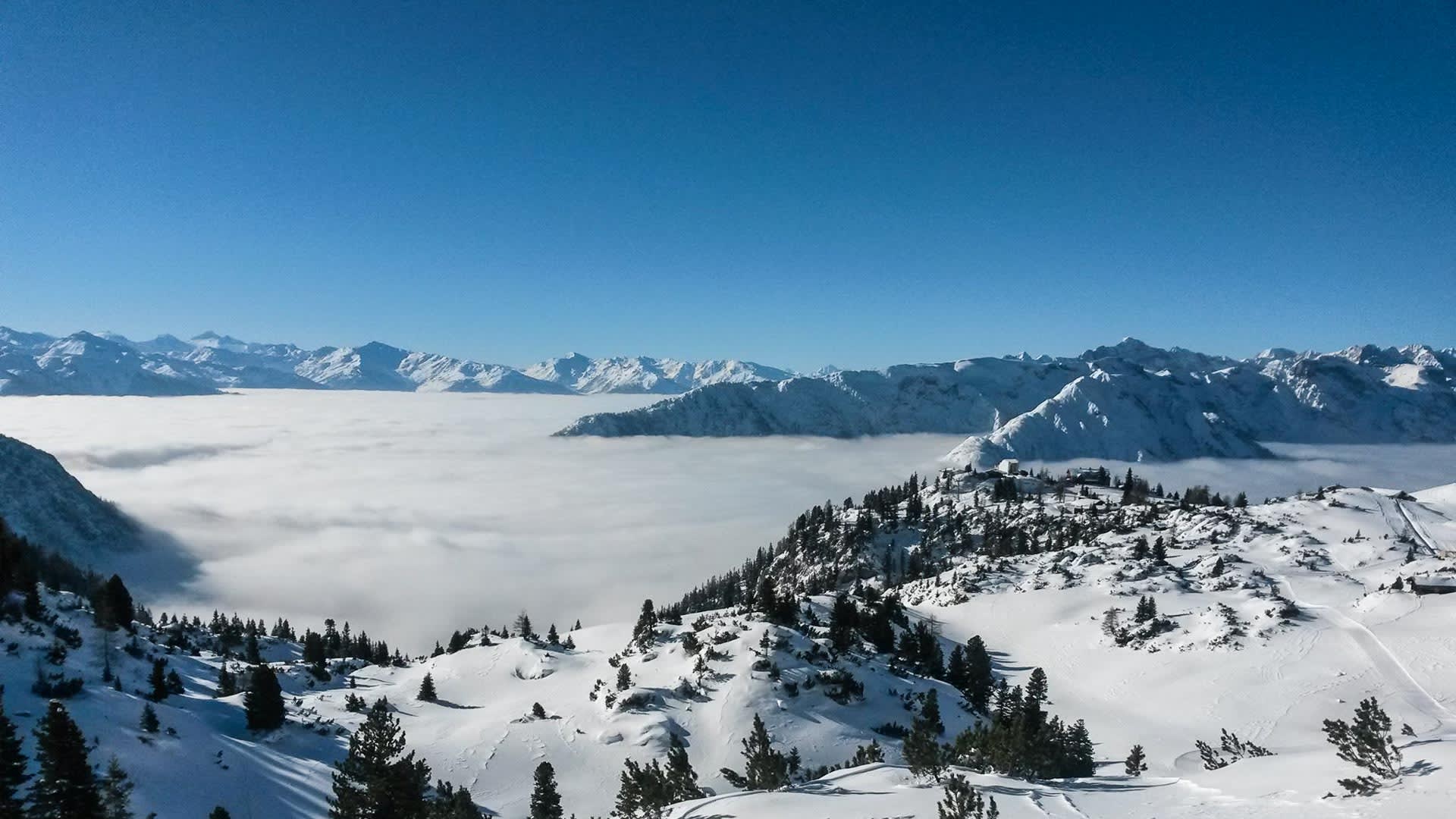 Skitour am Achensee: Panorama mit Nebelmeer über dem Tal und schneebedeckten Karwendelgipfeln im Hintergrund.