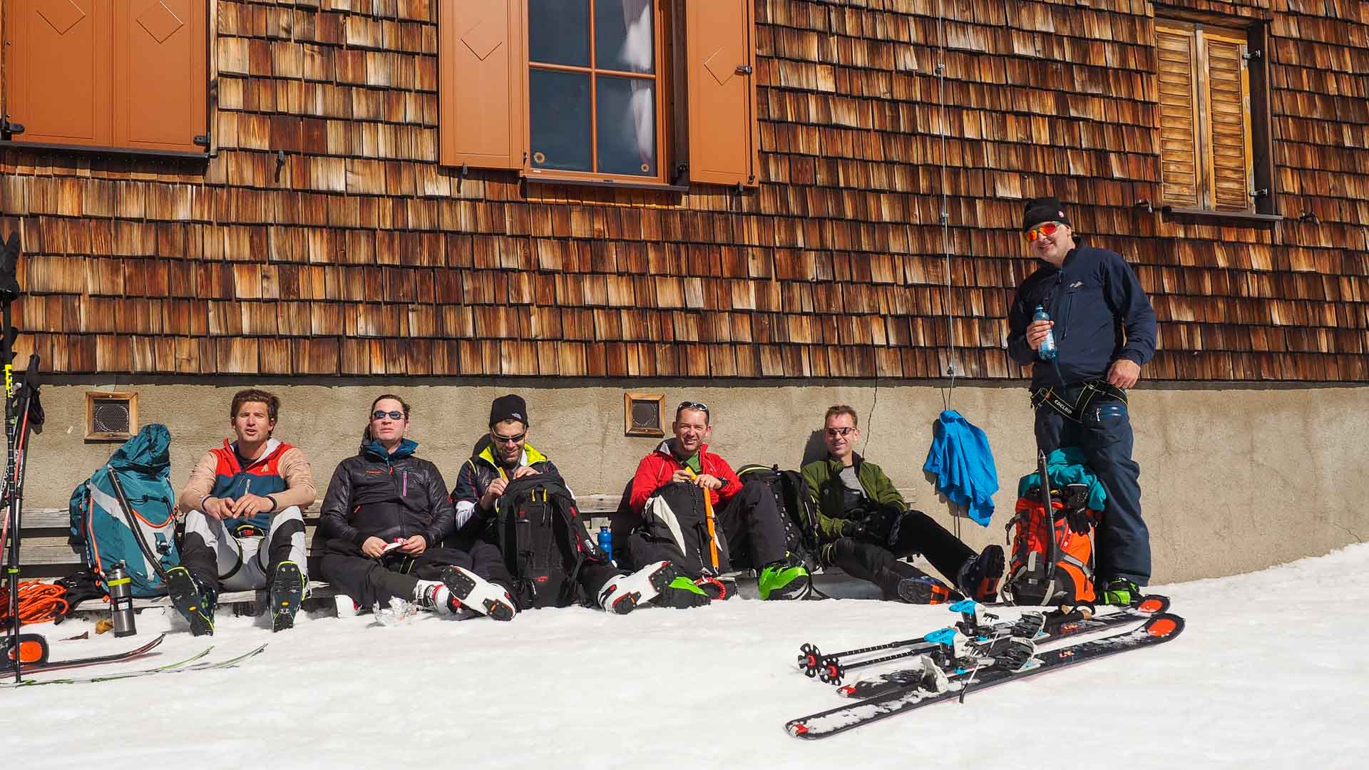 Sechs Skitourengeher machen Pause vor der Johannishütte am Großvenediger, Tourenski und Felle im Vordergrund.