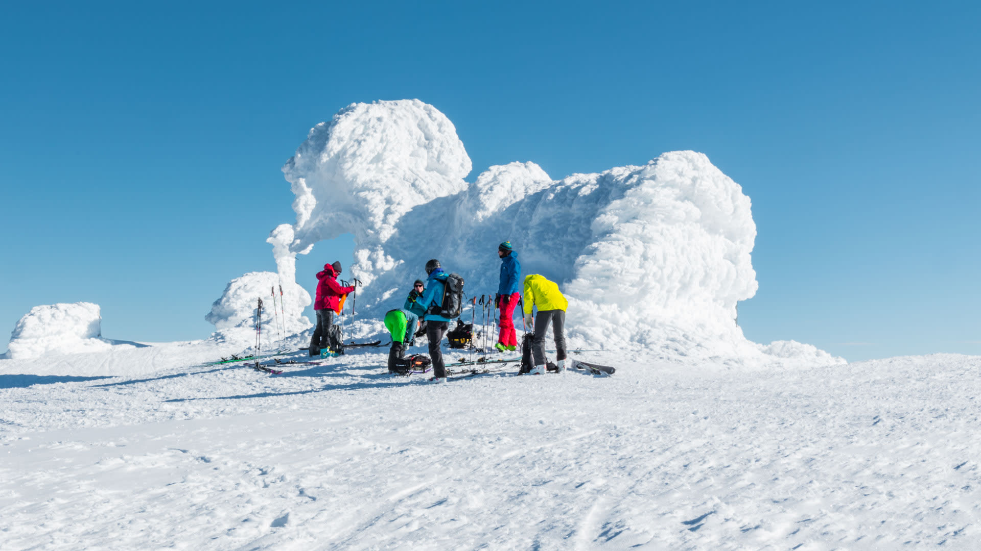 Fünf Skitourengeher pausieren auf einem Schneeplateaubereich in der polaren Skitouren-Region Spitzbergen.