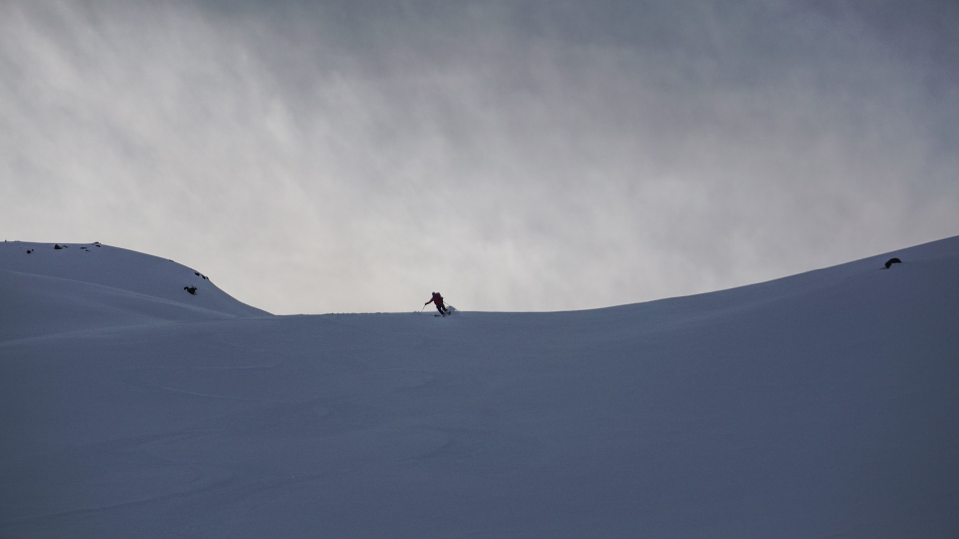 Ein Skitourengeher in roter Jacke fährt einen Tiefschneehang auf der Tour du Ciel ab.