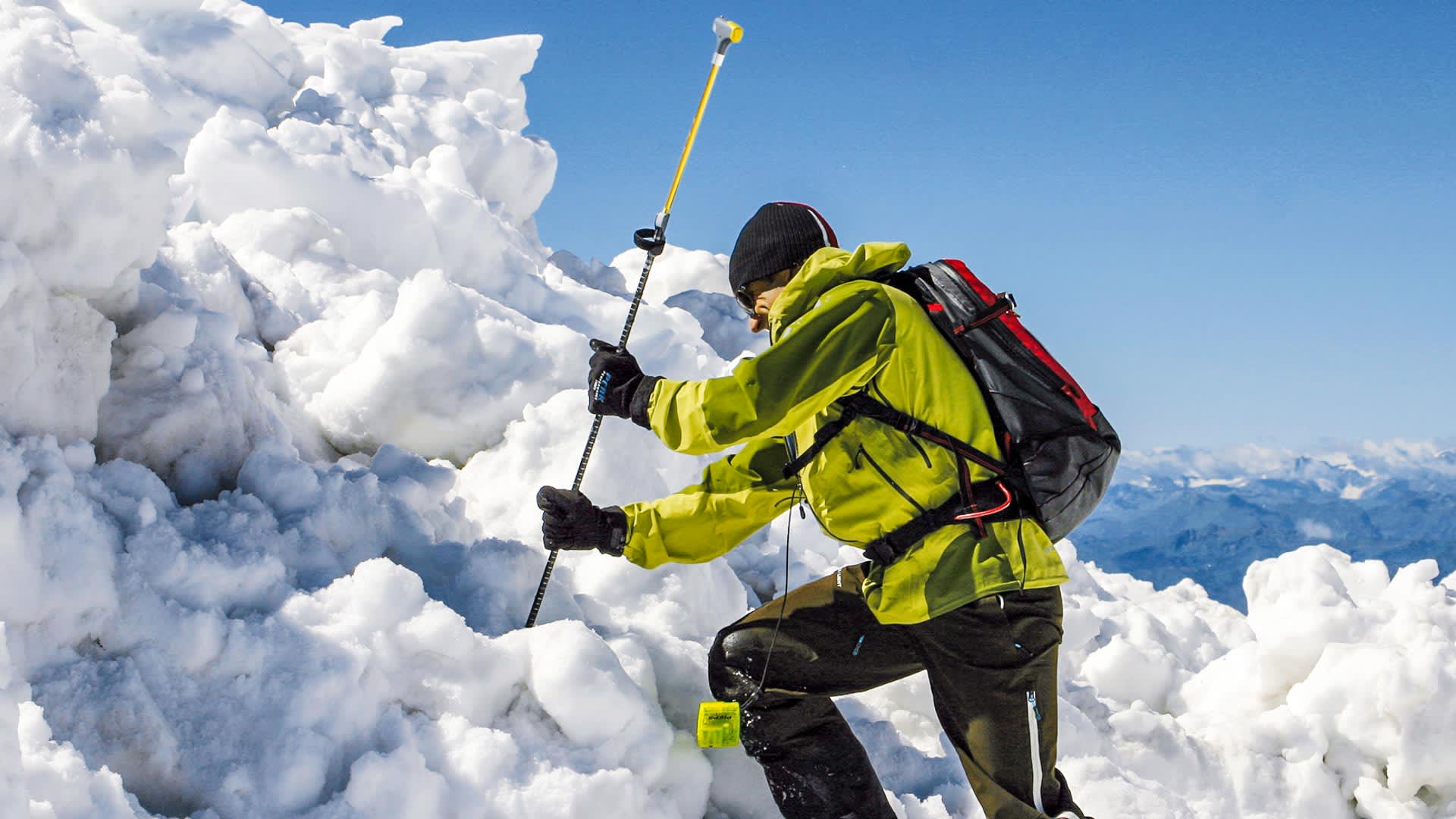 Skitourengeher mit Rucksack und Wanderstock navigiert durch zerklüftetes Schnee- und Eisgelände im Rofangebirge.