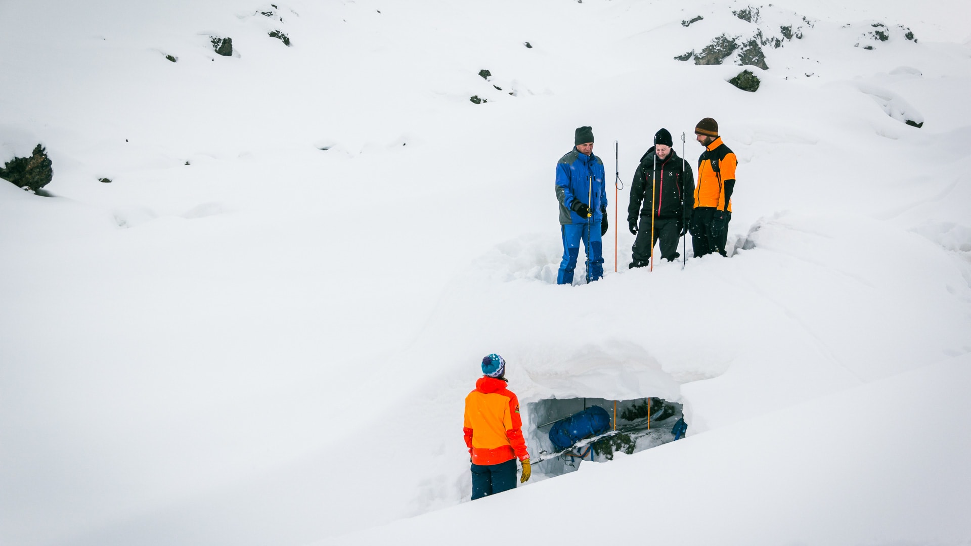 Vier Skitourengeher üben Lawinensondieren mit Sonden an einer Schneegrube an der Jamtalhütte in der Silvretta.