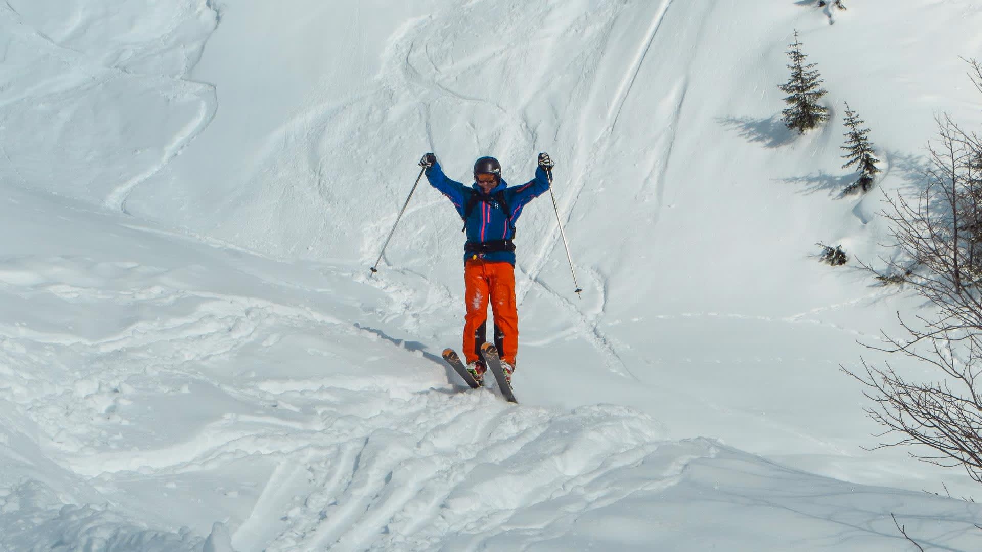 Skifahrerin in blauer Jacke fährt beim Tiefschneekurs Skitour einen steilen, unverspurten Pulverschneehang mit Schwungspuren