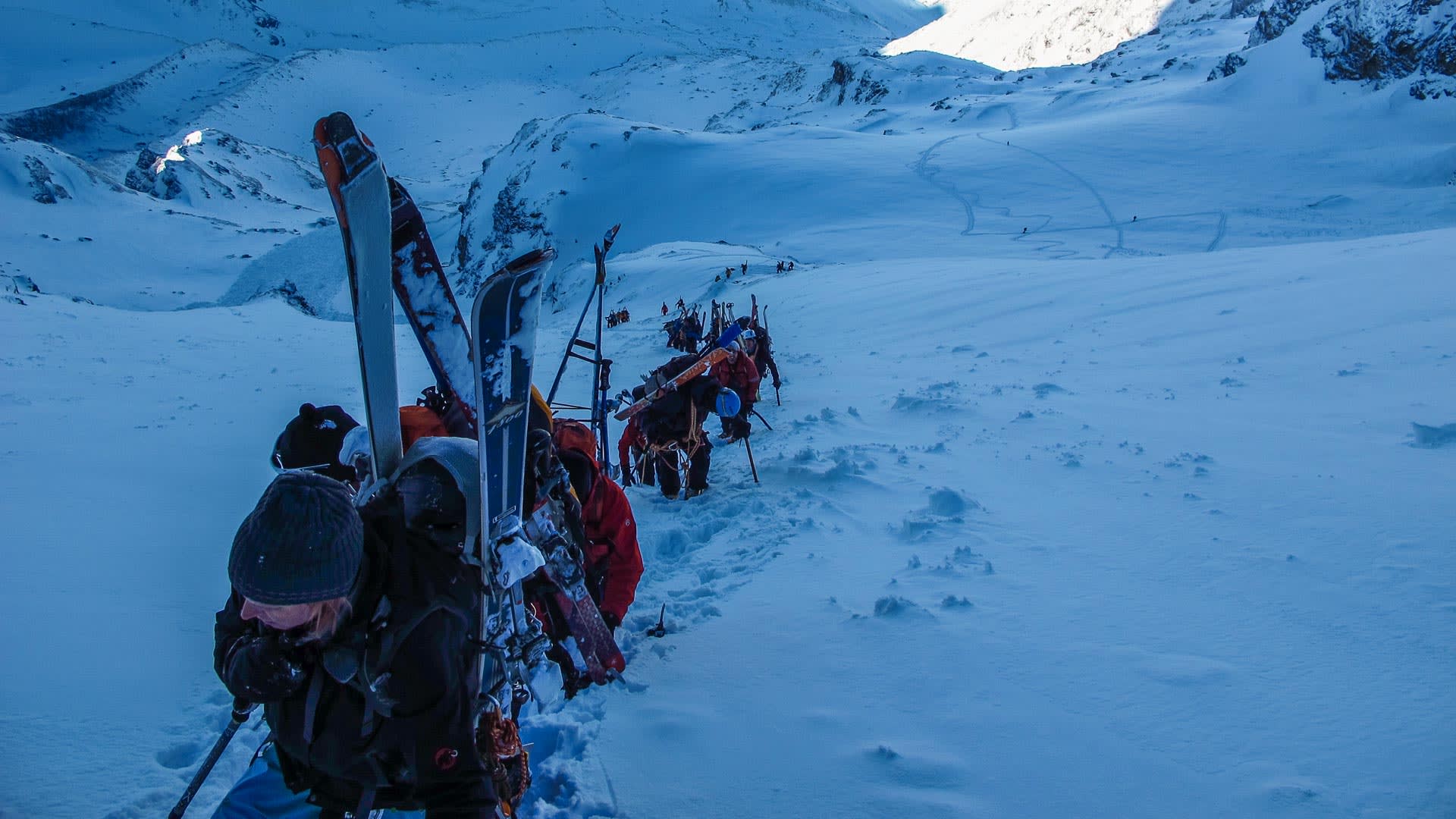 Gruppe von Skitourengehern trägt Tourenski am Rücken beim Aufstieg an der Schlüsselstelle ab der Valsorey Hütte auf der Haute Route.