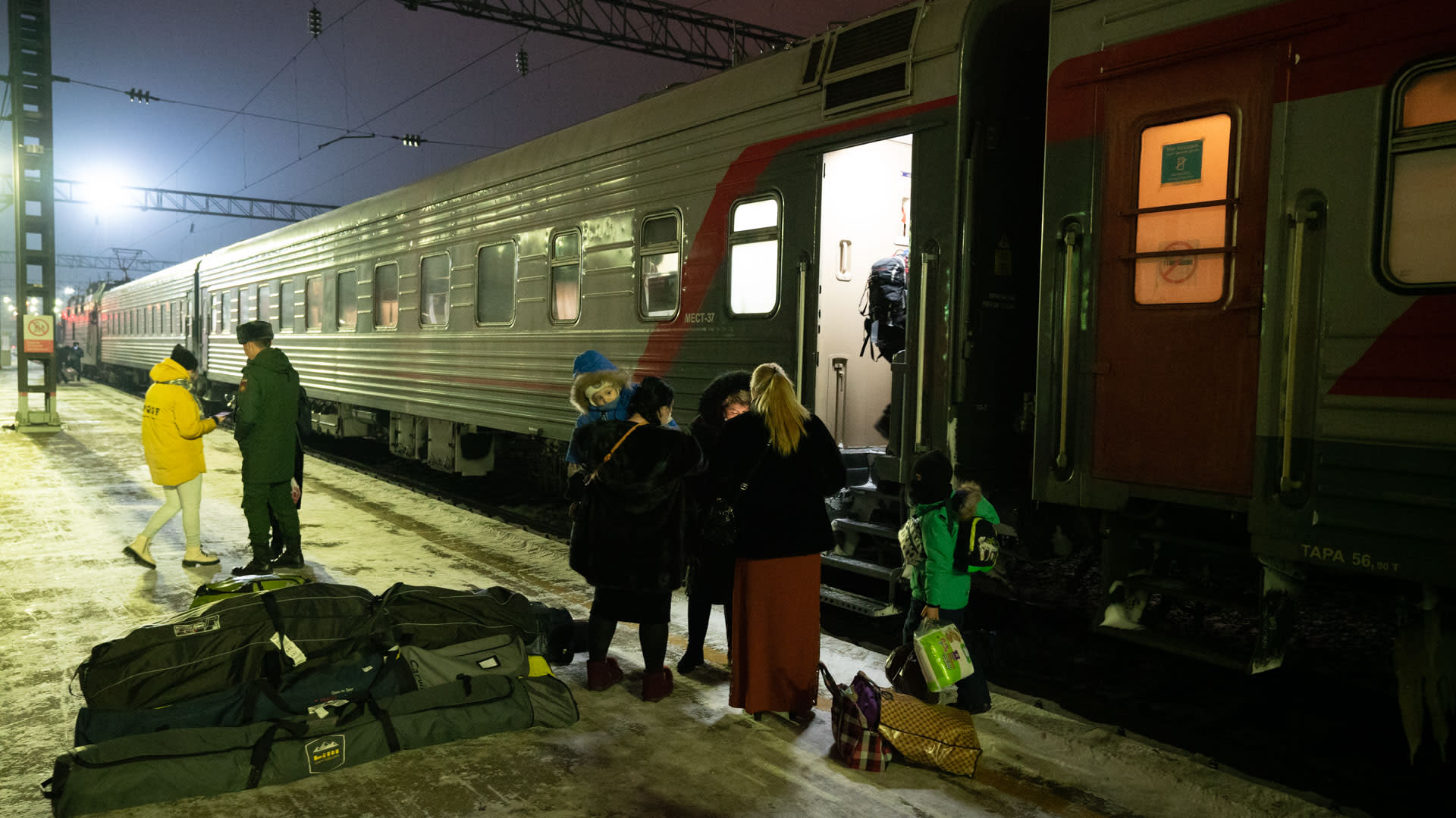 Skitourengeher mit Gepäck auf einem winterlichen Bahnsteig beim Gebietswechsel mit der Transsibirischen Eisenbahn.
