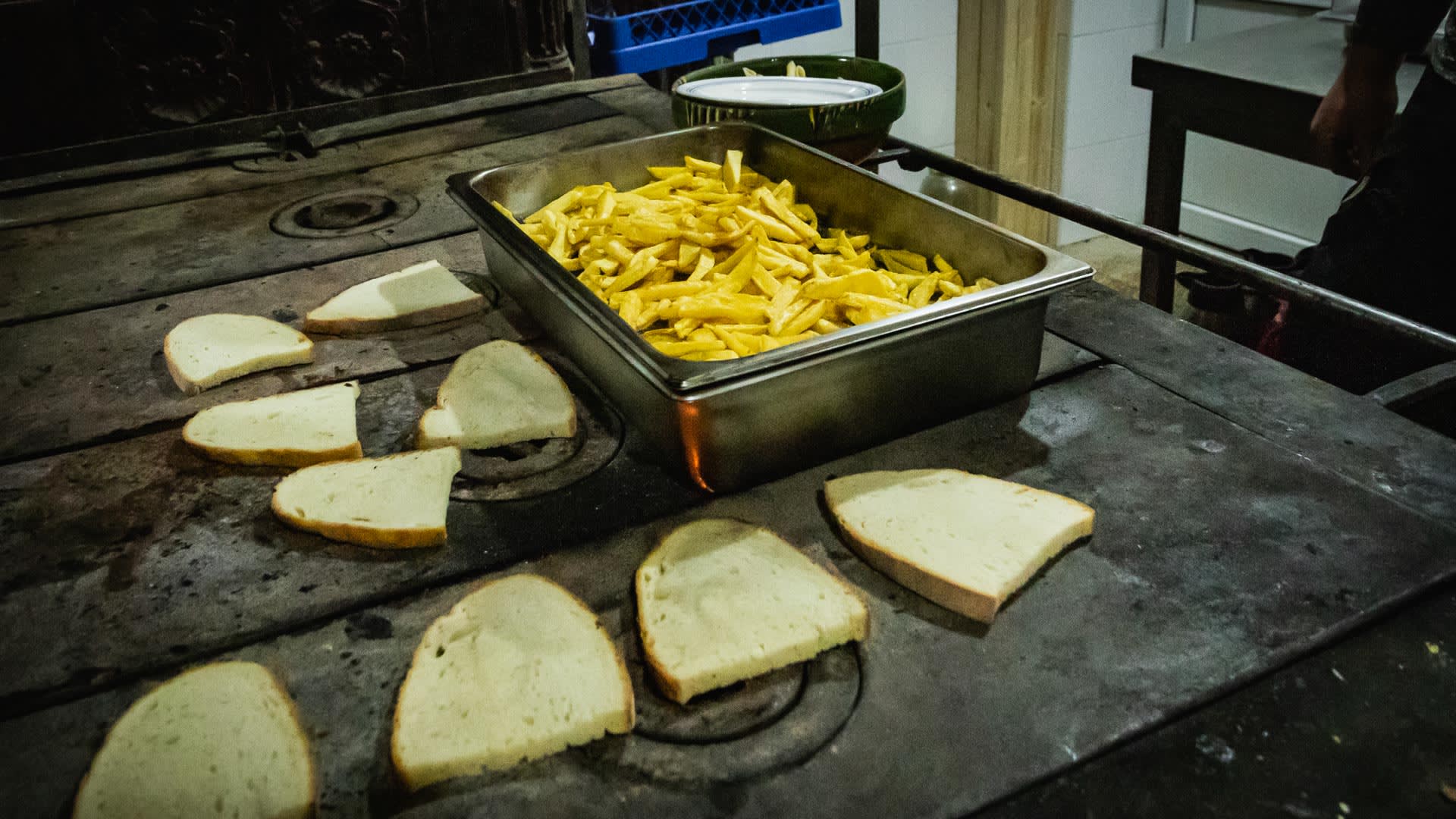 Brotscheiben und Pommes frites auf dem Herd der Negoiu-Hütte bei einer Skitourenreise in Rumänien.