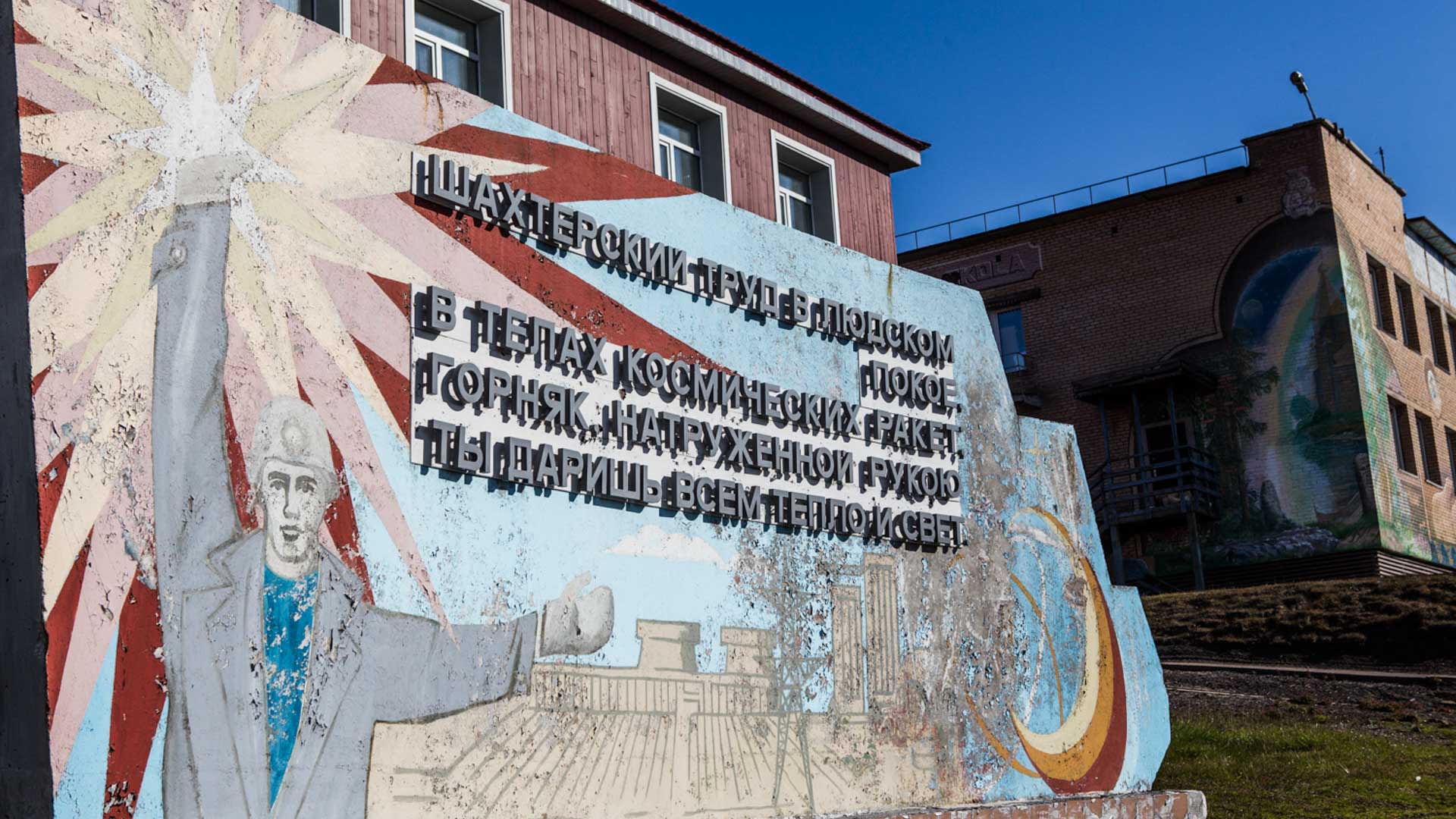 Trekking Spitzbergen: Verwittertes sozialistisches Wandrelief mit kyrillischer Inschrift und Bergarbeiter-Motiv in Barentsburg