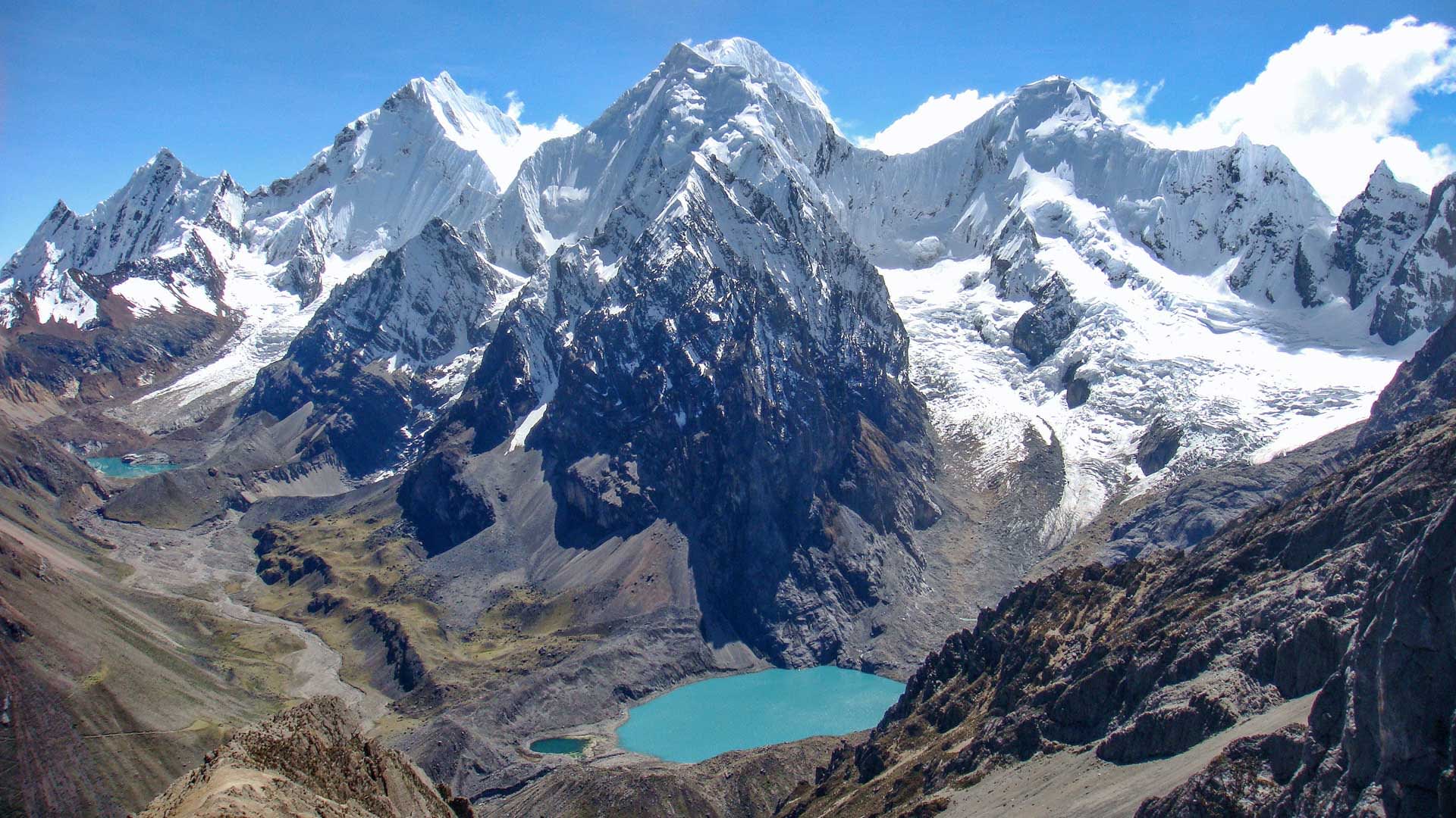 Trekking im Huayhuash: türkisblauer Jurausee im Talkessel mit Siula Grande und vergletscherten Gipfeln vom San Antonio Pass.