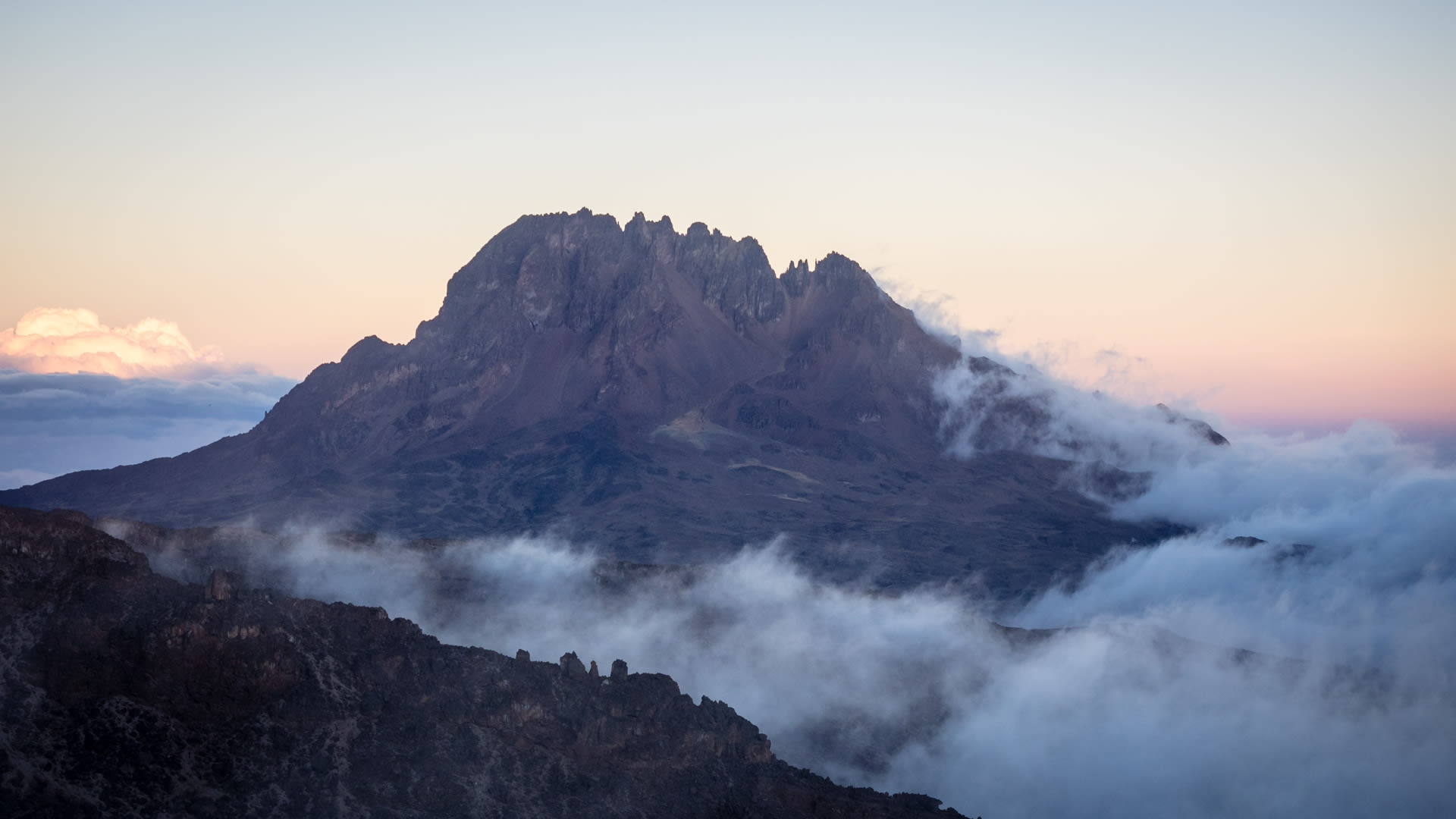 Das gezackte Mawenzi Massiv am Kilimandscharo erhebt sich bei Morgendämmerung aus einem Wolkenmeer.
