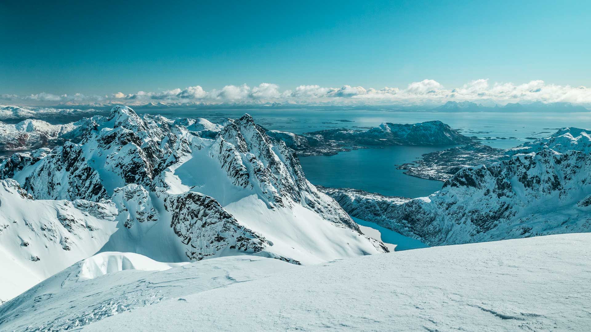 Winterwanderung auf den Lofoten: Panoramablick vom Geitgaljartind über schneebedeckte Gipfel und den Fjord.