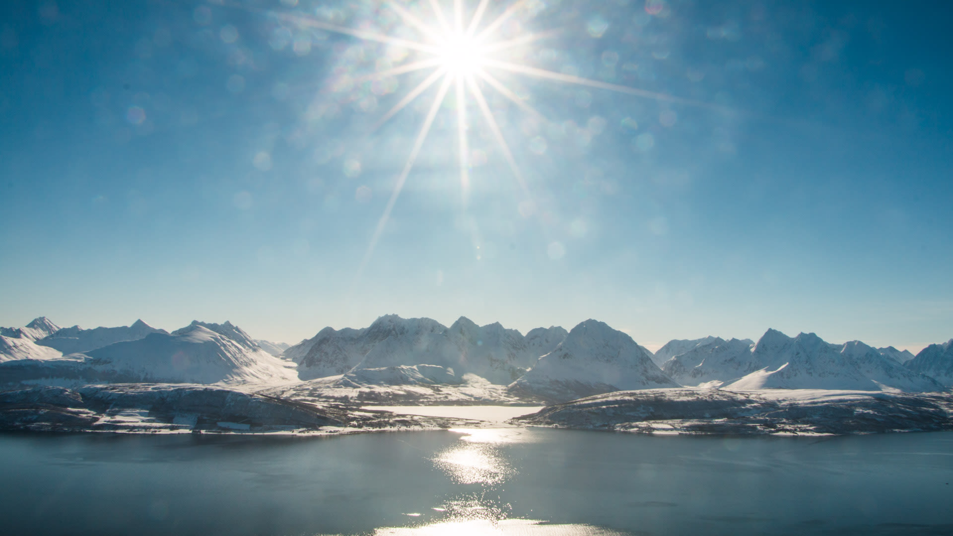 Skitour Ski and Sail Lyngen: Blick über den Fjord auf die schneebedeckten Gipfel der Lyngenalpen in Norwegen.