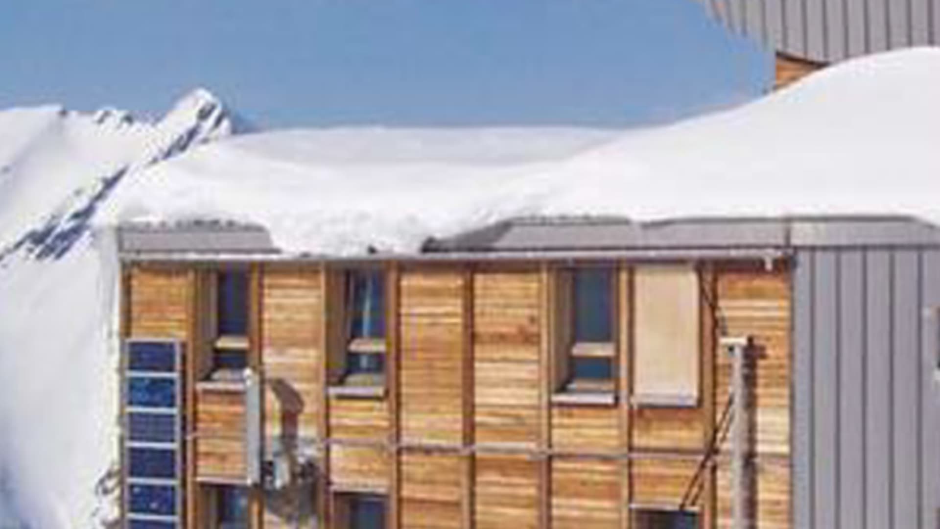 Das Refuge des Conscrits auf 2602 m zeigt moderne Holz-Metall-Architektur mit verschneitem Dach im Mont-Blanc-Massiv.